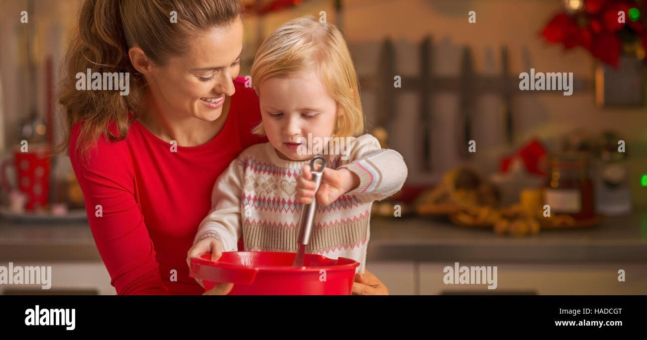 Heureuse maman et bébé en fouettant la pâte en cuisine Décoration de Noël Banque D'Images