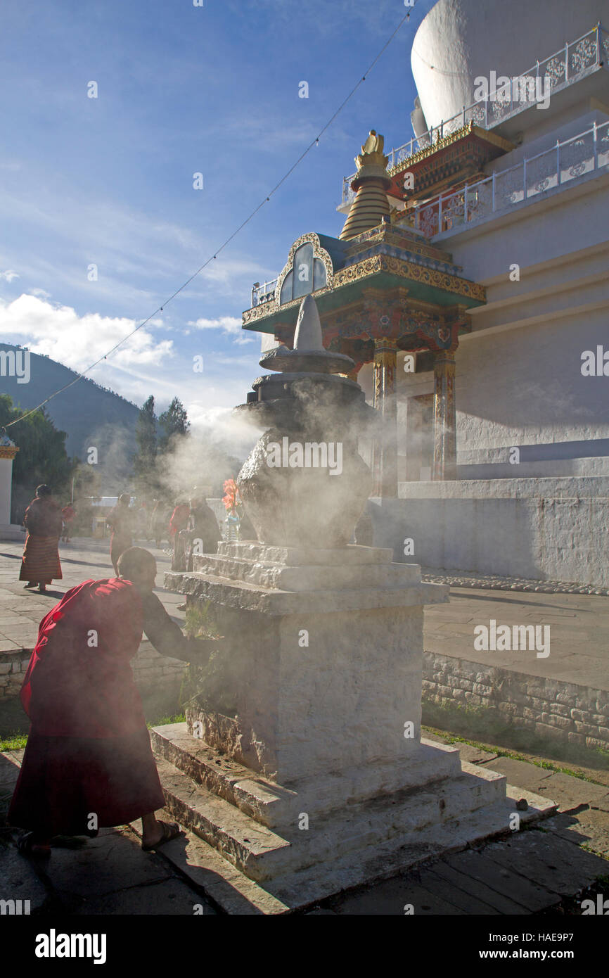 Monk attisant une urne au National Memorial Chorten à Thimphu Banque D'Images