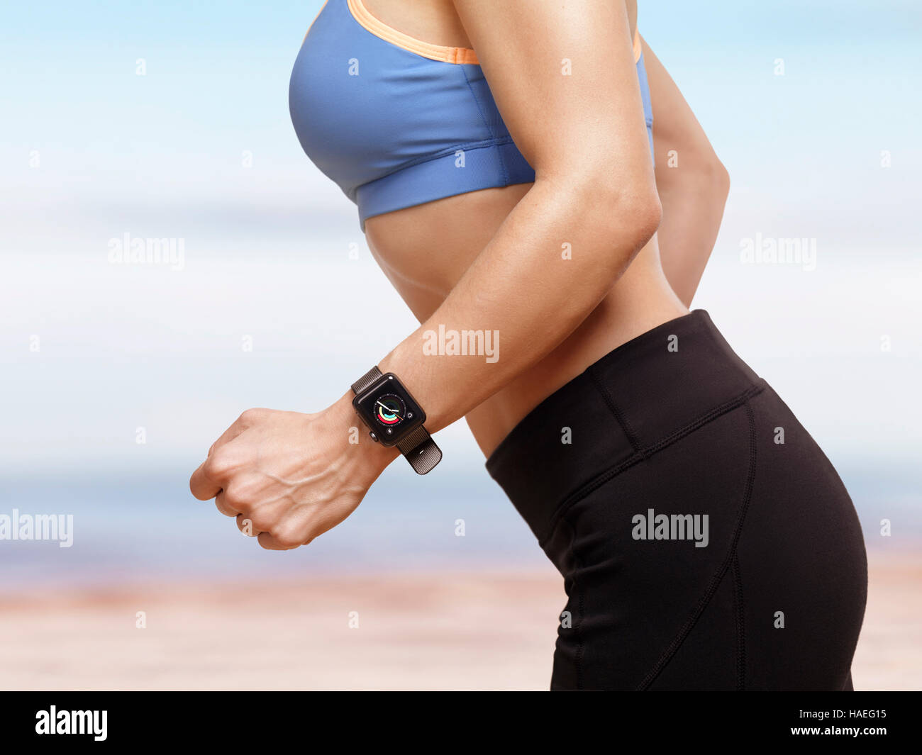 Licence disponible sur MaximImages.com - Femme jogging à l'extérieur à la plage avec Apple Watch smartwatch sur son poignet affichant l'activité quotidienne et exer Banque D'Images