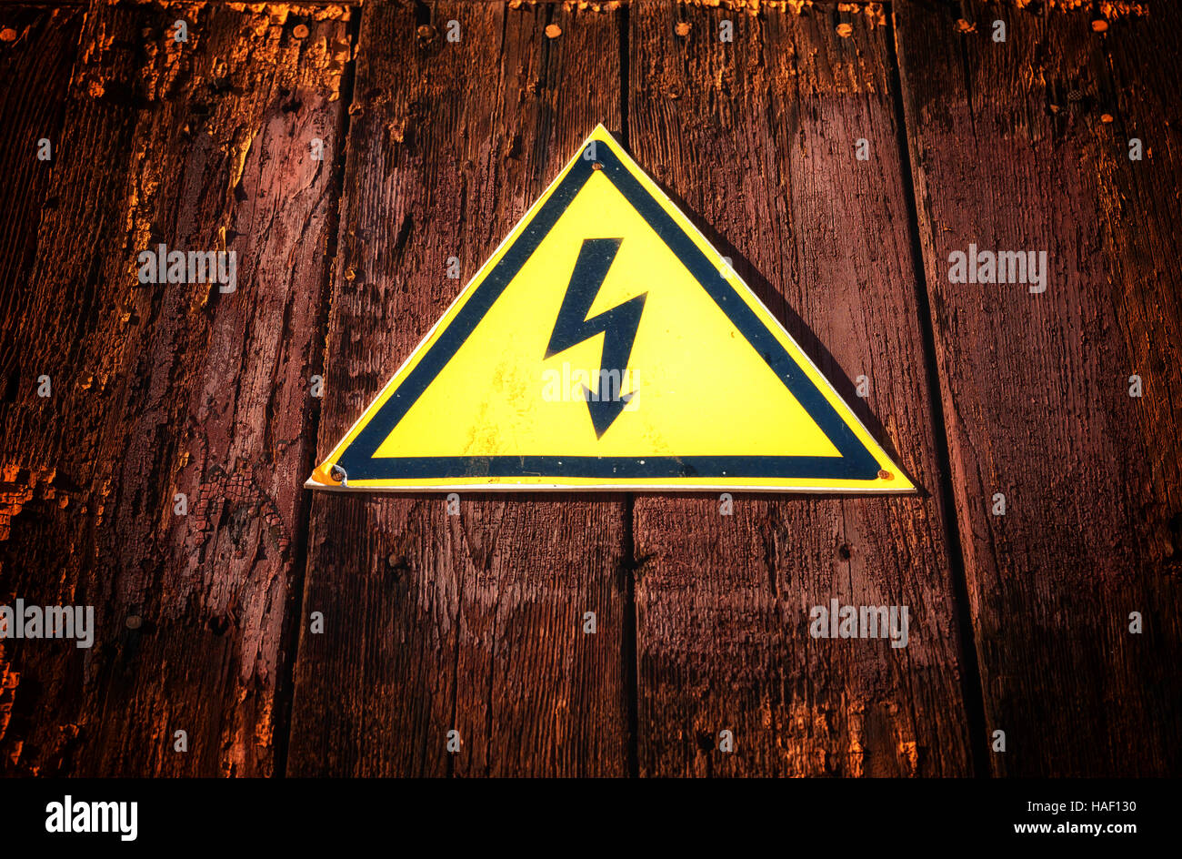 En forme d'avertissement jaune de l'électricité avec une bouilloire noire sur un bois sombre de style grunge background. Banque D'Images