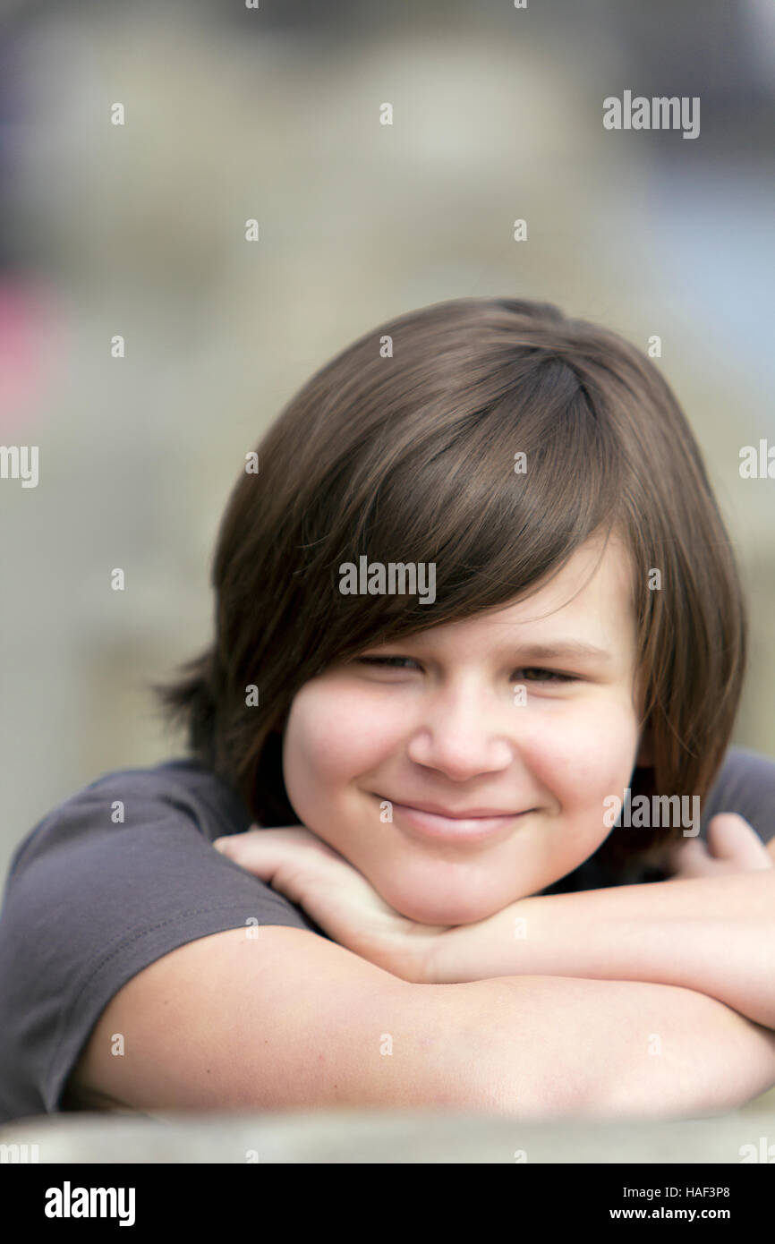 Jeune fille posant sa tête sur ses bras et souriant Banque D'Images