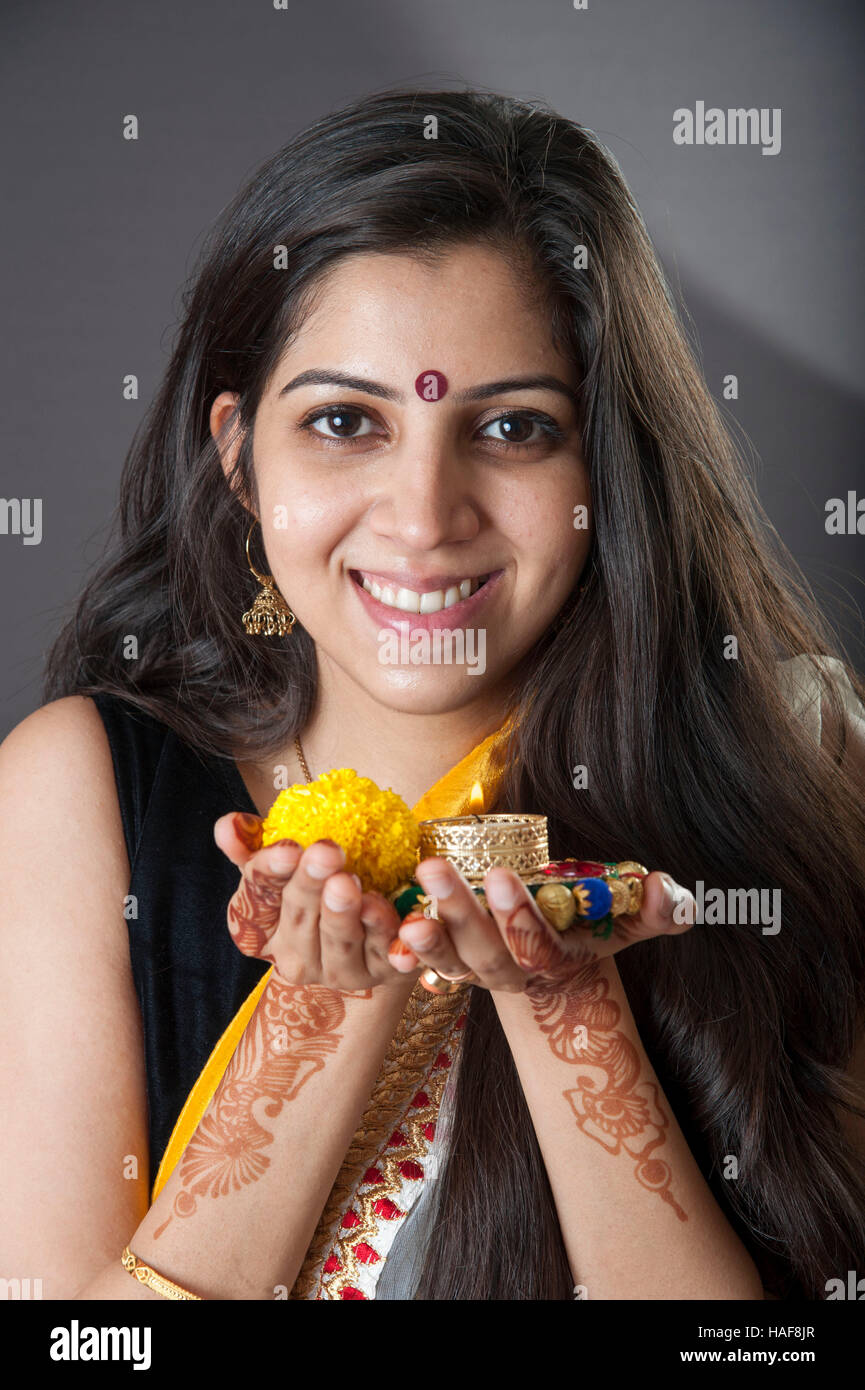 Une fille souriante et tenant une lampe à huile traditionnelle Diwali diya avec fleur offrande religieuse et souriant Mumbai Inde Banque D'Images