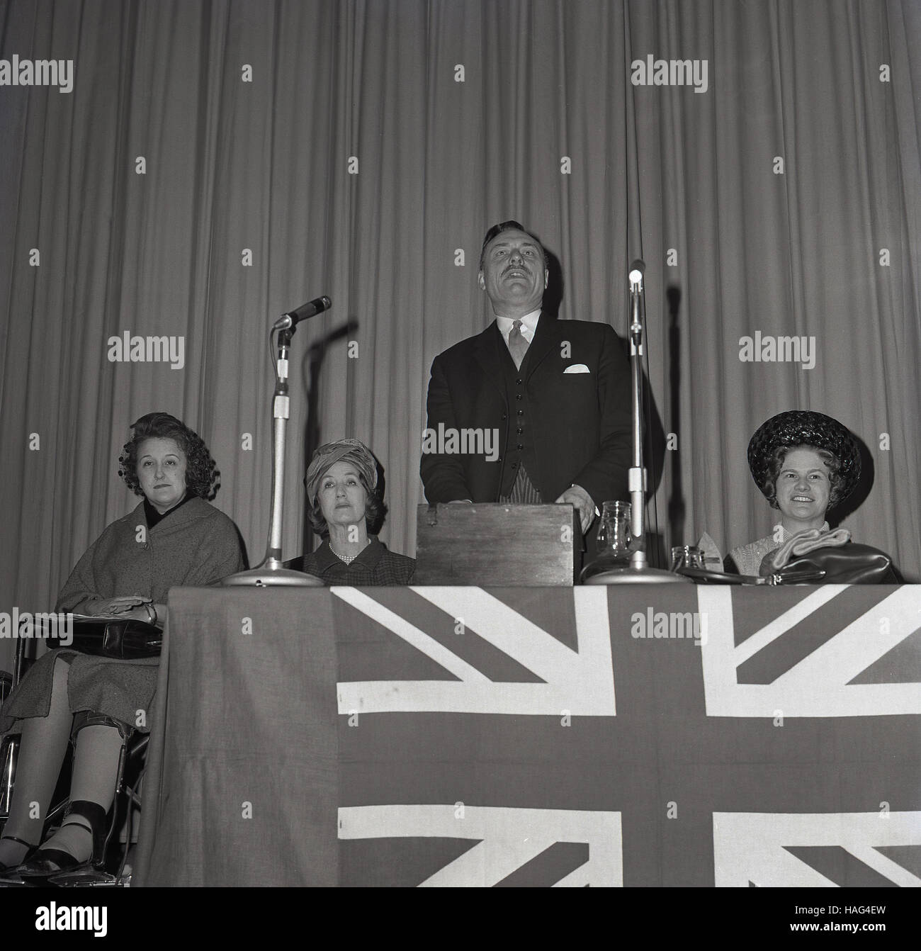1965, historique, le politicien britannique Enoch Powell, avec sa femme à côté de lui, faisant un discours à l'Assemblée de l'Arrondissement Mairie, Aylesbury, Buckinghamshire, Angleterre. Banque D'Images