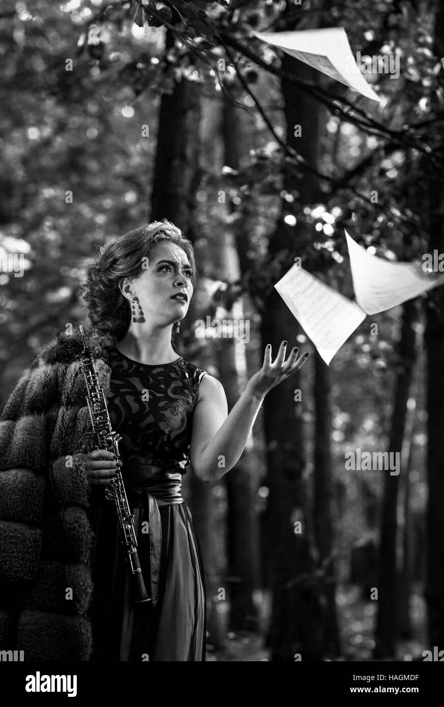 Le noir et blanc portrait de jeune femme émotionnelle jeter les feuilles de musique et la tenue d'un hautbois dans la main Banque D'Images