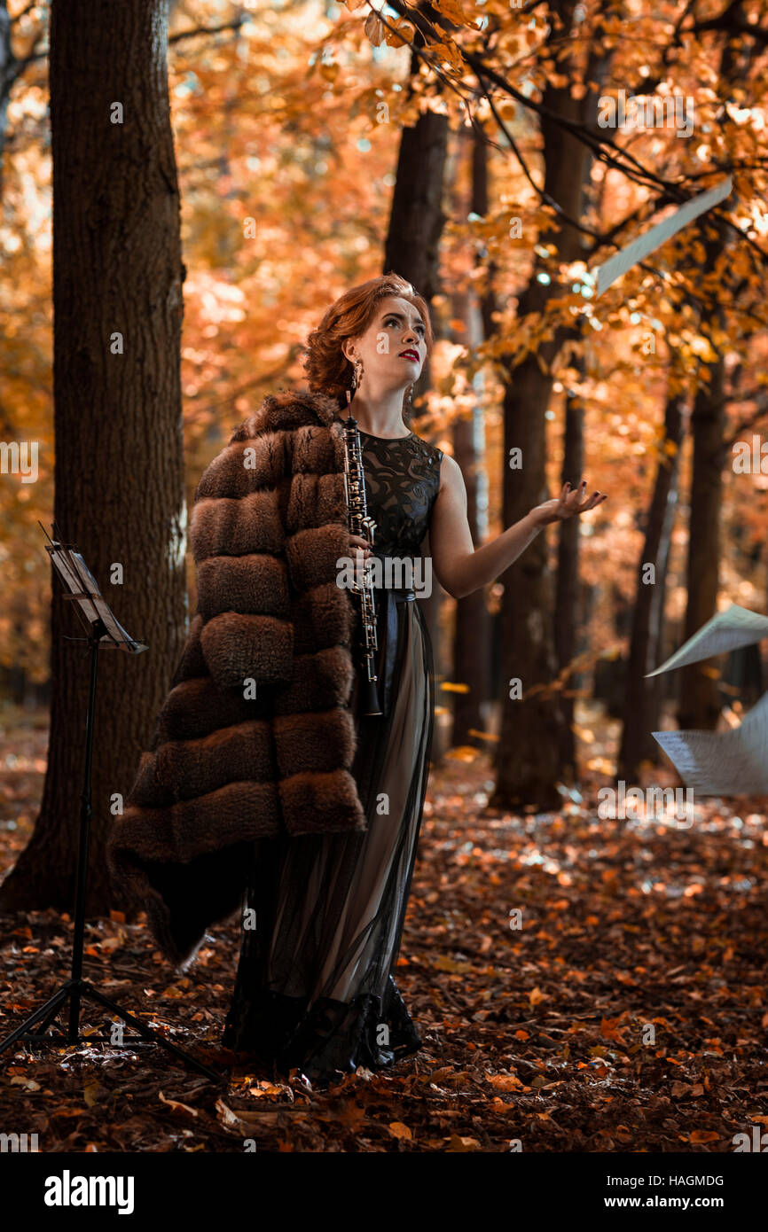 Jeune femme émotionnelle jeter les feuilles de musique et la tenue d'un hautbois dans la main Banque D'Images