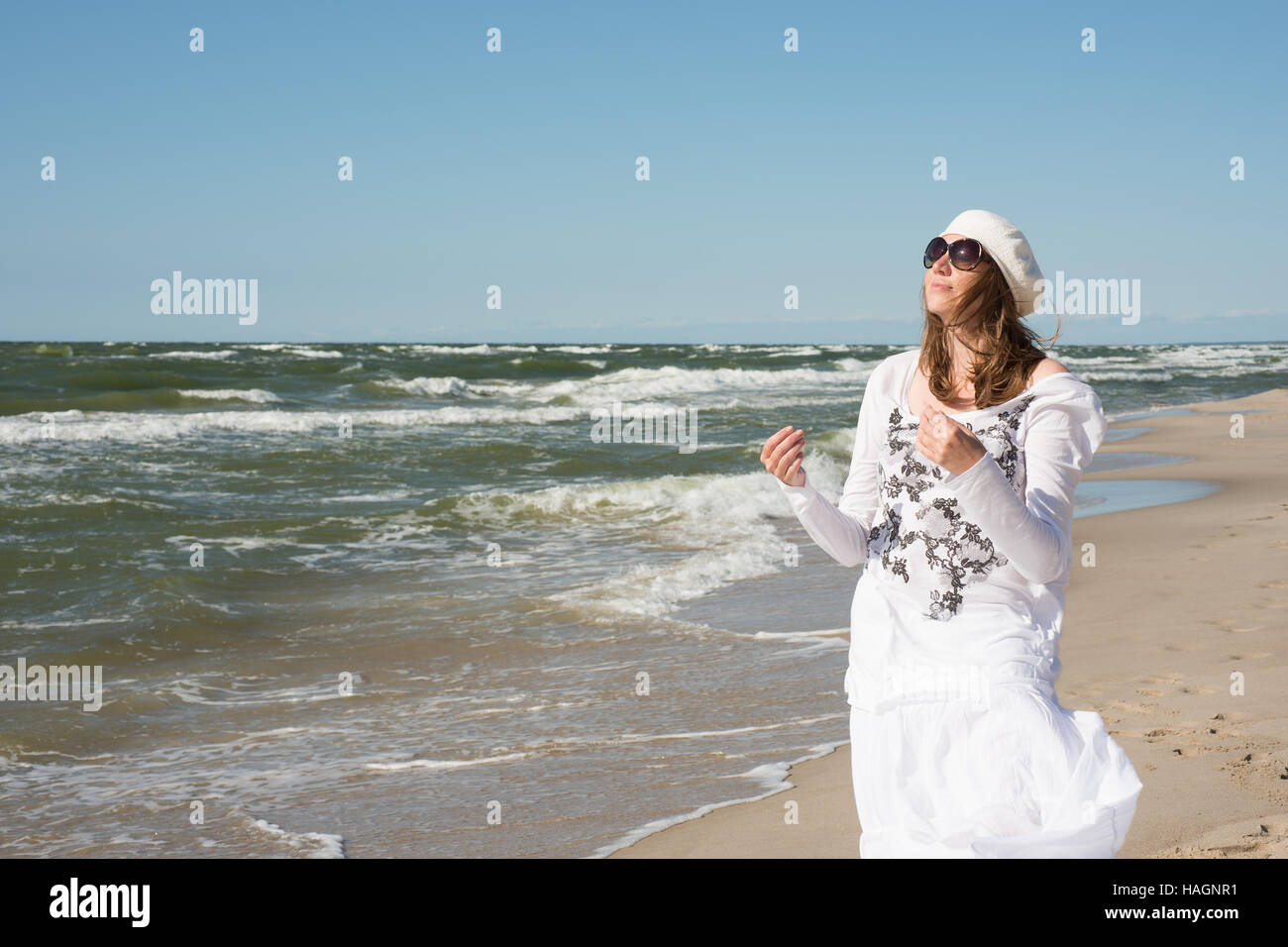 Femme en robe blanche danser près de la mer Banque D'Images