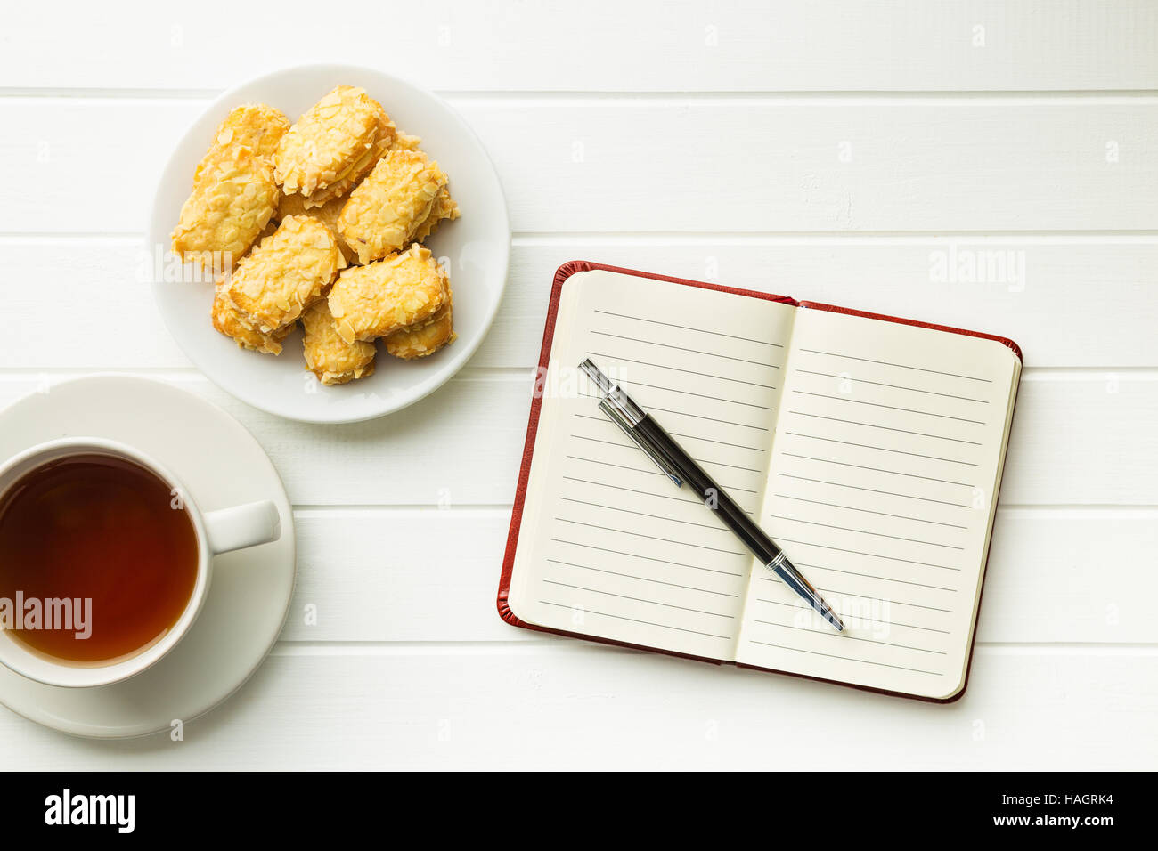 Le bloc-notes avec stylo blanc et des biscuits avec du thé. Vue d'en haut. Banque D'Images