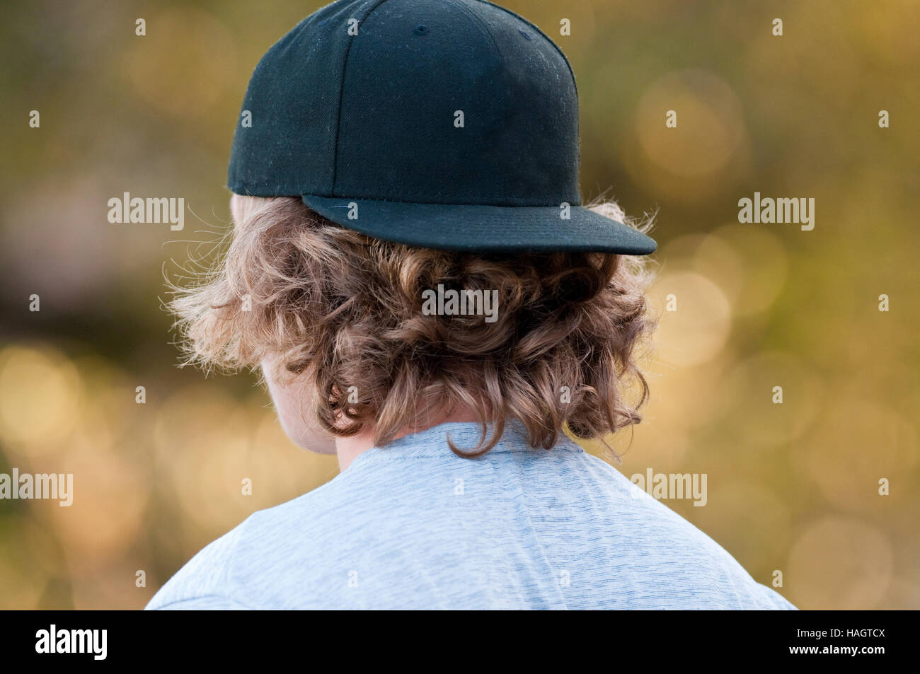 Adolescent aux cheveux longs à l'écart dans une casquette de baseball noire  Photo Stock - Alamy