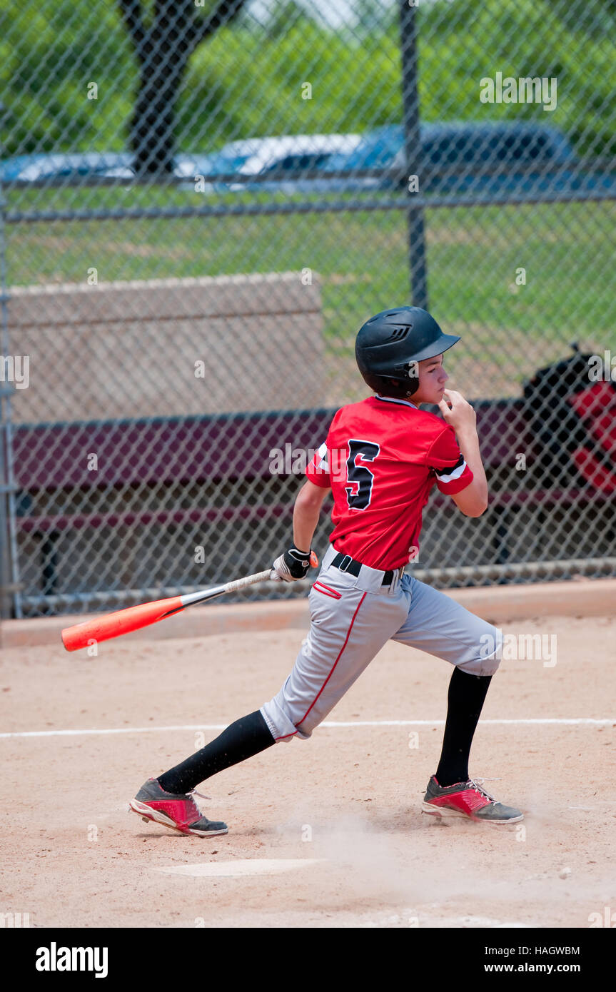 Youth baseball player batting la balle lors d'une partie. Banque D'Images