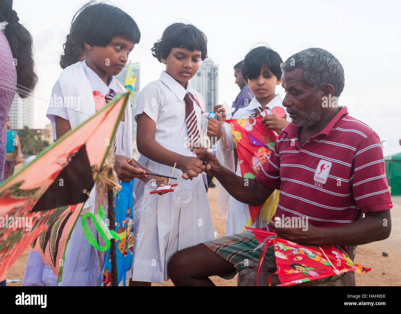 Les enfants de l'école visionner une man making kites, Galle Face Green, Colombo, Sri Lanka. Banque D'Images