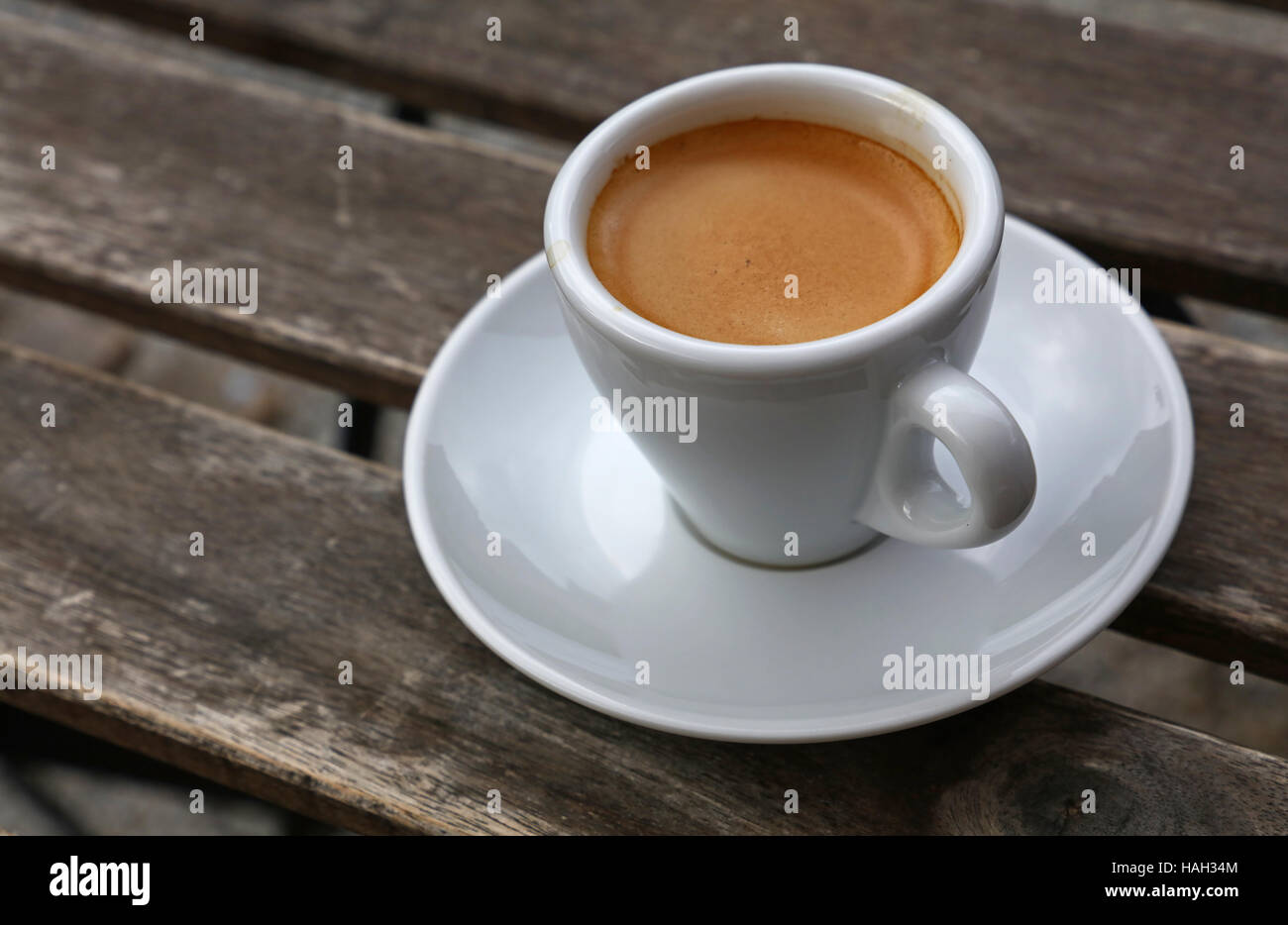 Machine à café expresso crema brown tourné en mousse blanc porcelaine tasse avec soucoupe sur table en bois vintage, Close up, high angle view Banque D'Images