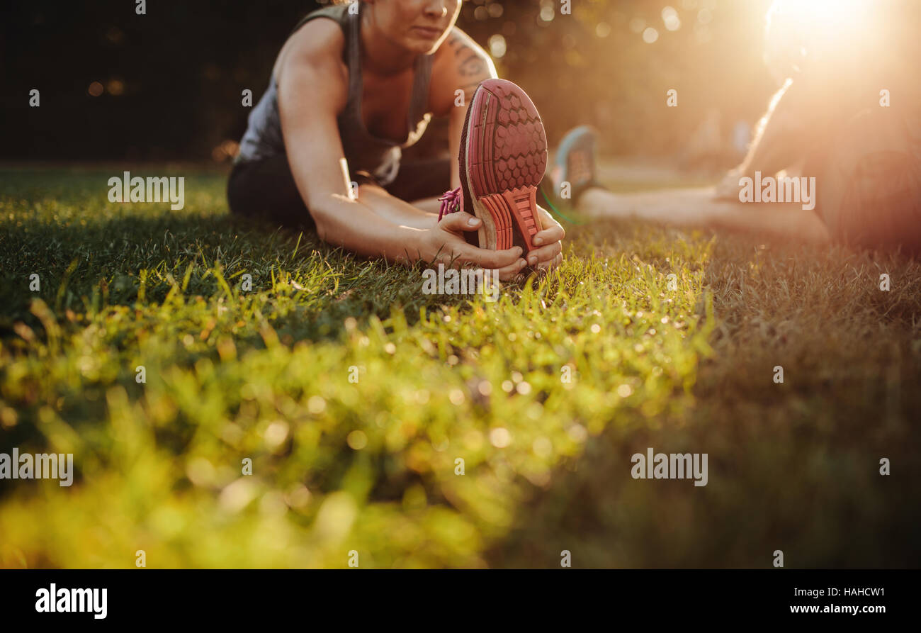 Cropped shot of female doing stretching exercice dans parc. Femme assise sur l'herbe et de l'échauffement. Banque D'Images