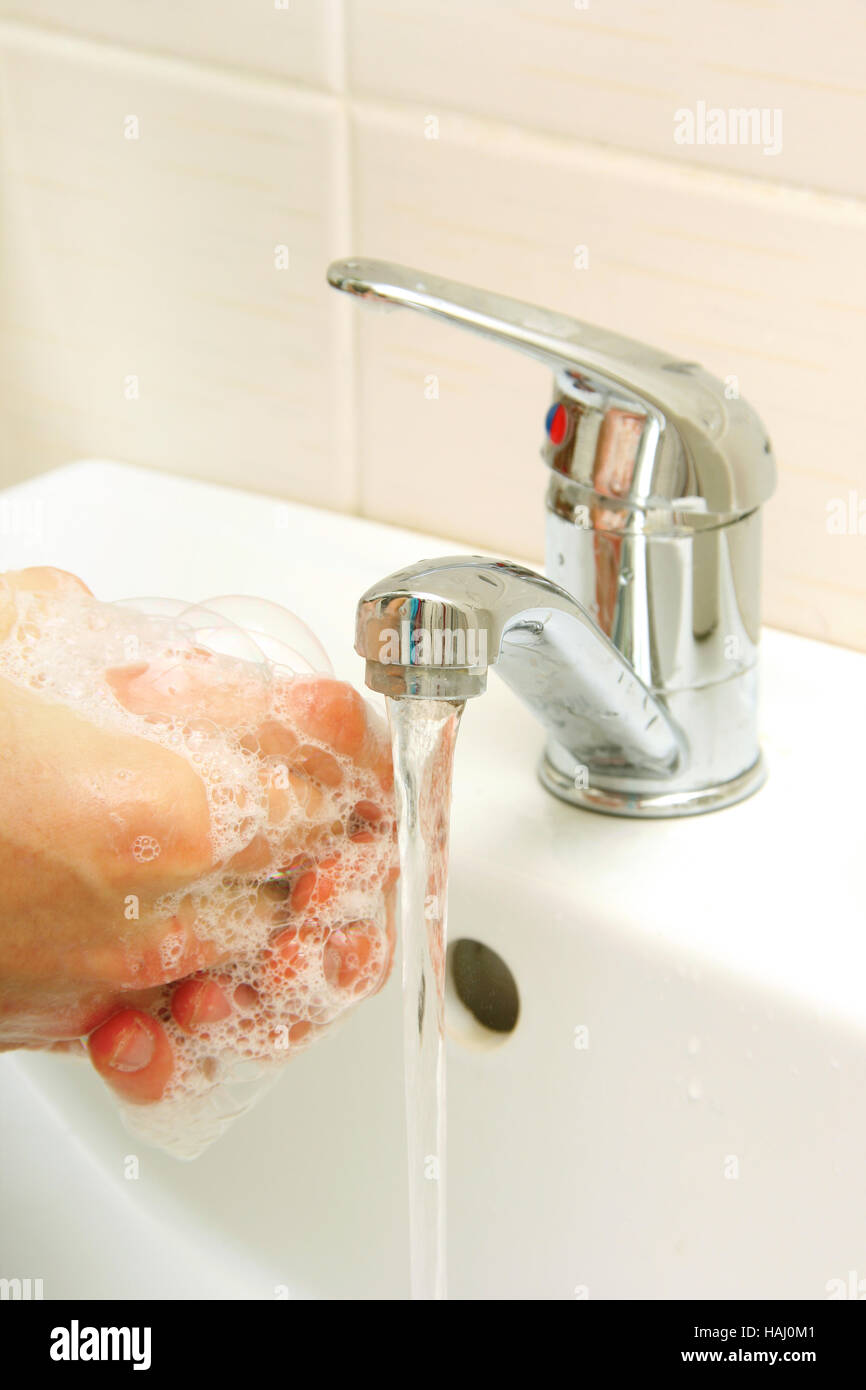 Les mains couvertes avec du savon d'être lavé dans l'évier Banque D'Images