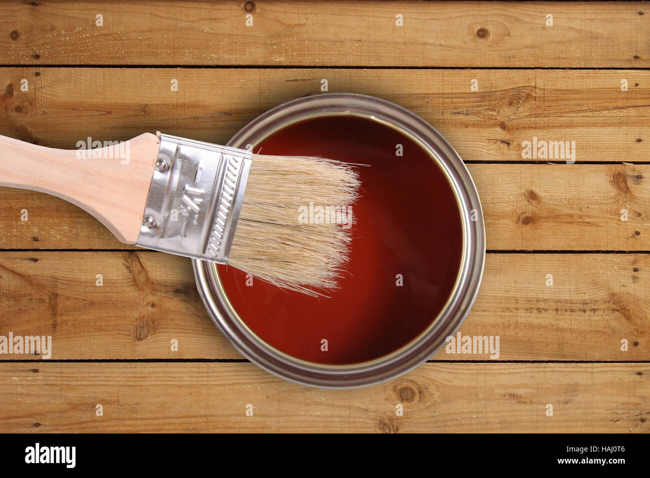La peinture rouge peut à l'aide d'un pinceau sur plancher en bois Banque D'Images