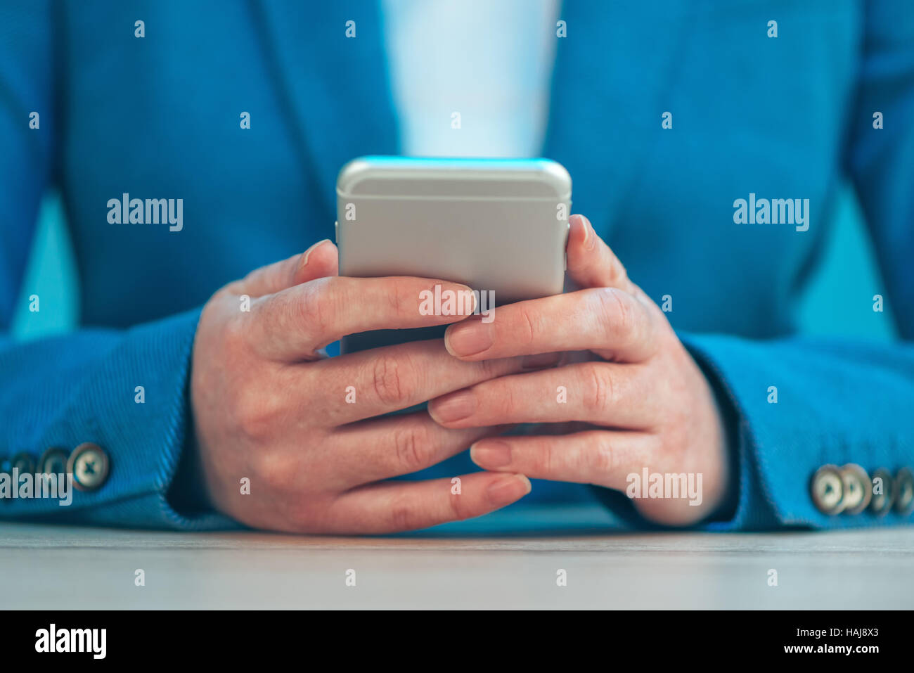 Businesswoman using smartphone, Close up femme les mains dans un élégant costume bleu holding mobile phone, selective focus Banque D'Images