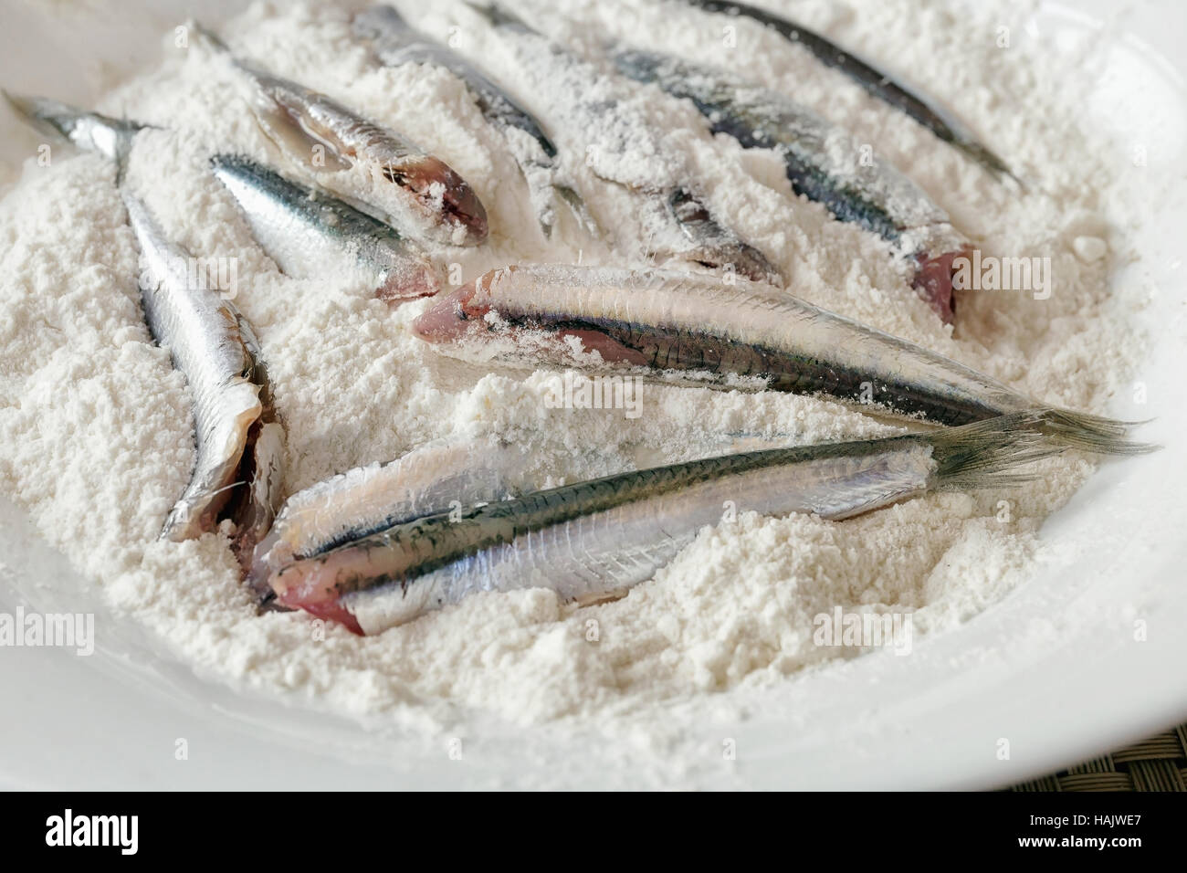 Anchois panés, propre et prêt à être cuisiné. L'anchois dans le plat rempli de la farine blanche. Frire dans l'huile. Banque D'Images