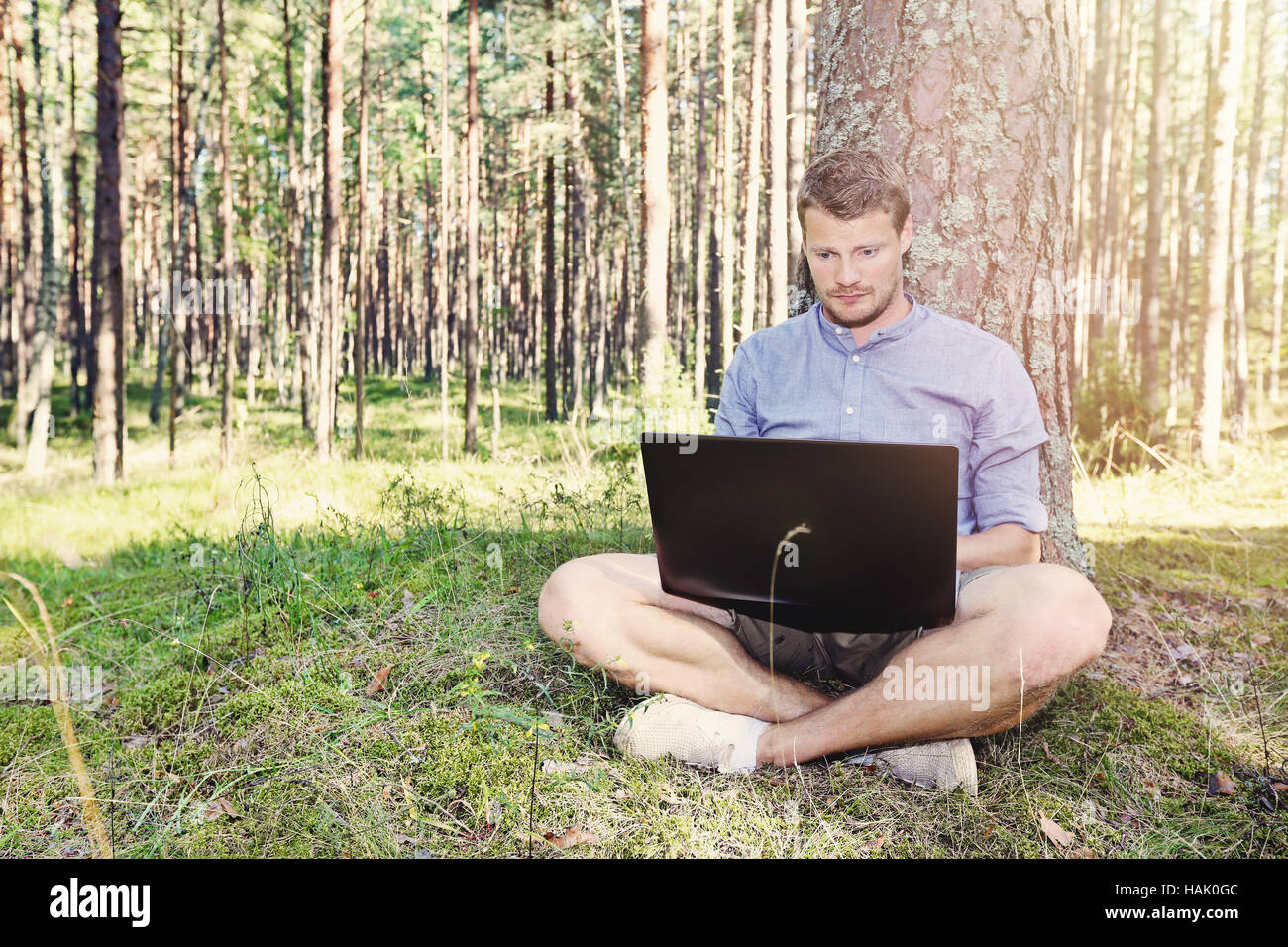 Jeune homme travailler avec son ordinateur portable à l'extérieur dans la nature Banque D'Images