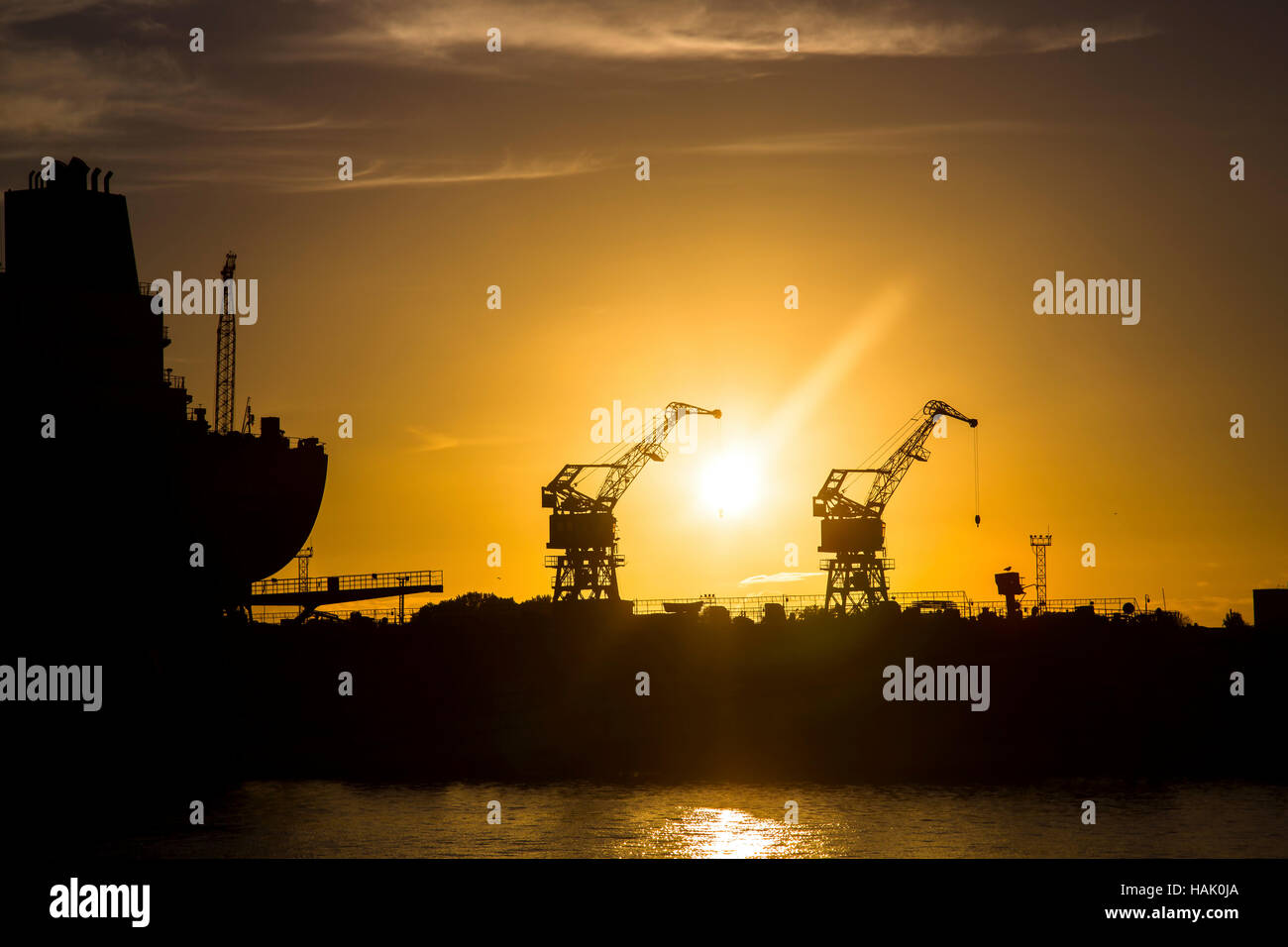 Chantier naval à coucher du soleil. silhouettes de grues et d'expédier Banque D'Images