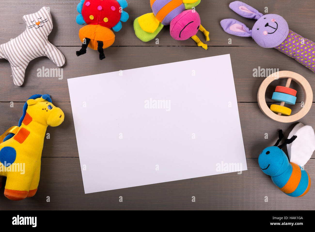 Jouets bébé en peluche sur fond de bois avec feuille de papier vierge Banque D'Images