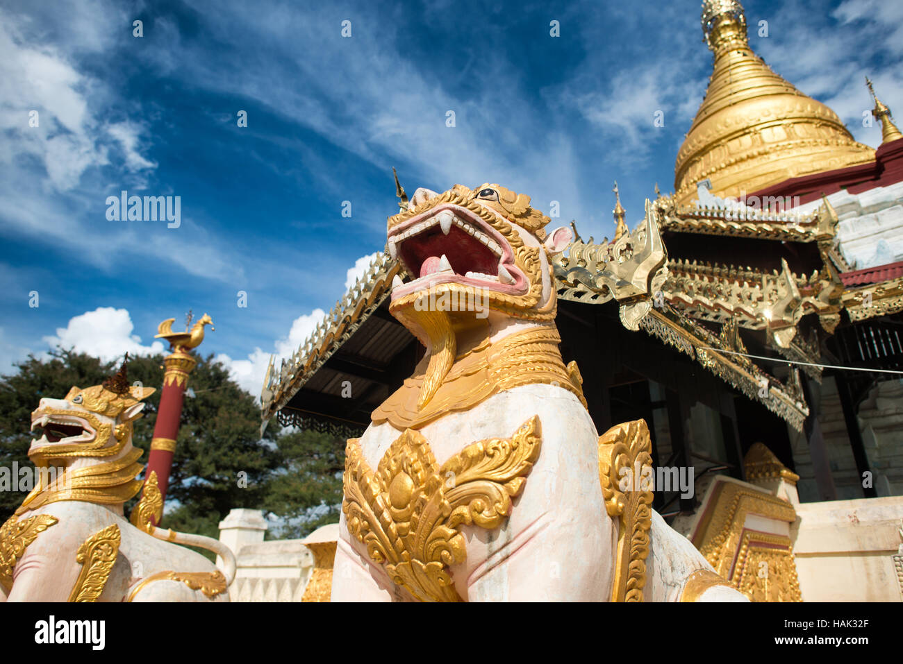 Shwe Kyaung U Temple Chinthe statues Bagan Myanmar // BAGAN, Myanmar — statues de gardien de lion ornées connues sous le nom de stand de chinthe devant le stupa doré et architecture élaborée du temple Shwe Kyaung U . Le temple bouddhiste du XVIIIe siècle, documenté comme Monument 2007 dans l'inventaire architectural de Pierre Pichard, est situé dans un monastère au nord-est de Pagan près du village de Taungbi. Le temple présente une construction traditionnelle en maçonnerie de briques avec un pavillon en bois distinctif ajouté sur sa face ouest, reflétant les adaptations faites pour servir la communauté monastique résidente. Shwe Kyaung U Temple représ Banque D'Images
