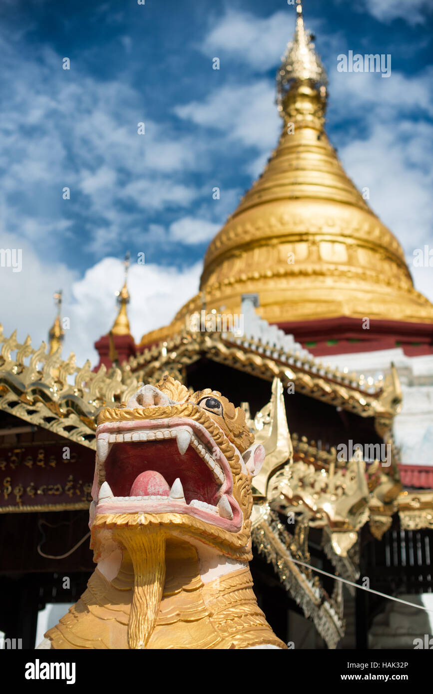 Shwe Kyaung U Temple Chinthe Guardian Bagan Myanmar // BAGAN, Myanmar — statues de gardien de lion ornées connues sous le nom de stand de chinthe devant le stupa doré et architecture élaborée du temple Shwe Kyaung U. Le temple bouddhiste du XVIIIe siècle, documenté comme Monument 2007 dans l'inventaire architectural de Pierre Pichard, est situé dans un monastère au nord-est de Pagan près du village de Taungbi. Le temple présente une construction traditionnelle en maçonnerie de briques avec un pavillon en bois distinctif ajouté sur sa face ouest, reflétant les adaptations faites pour servir la communauté monastique résidente. Shwe Kyaung U Temple Repre Banque D'Images