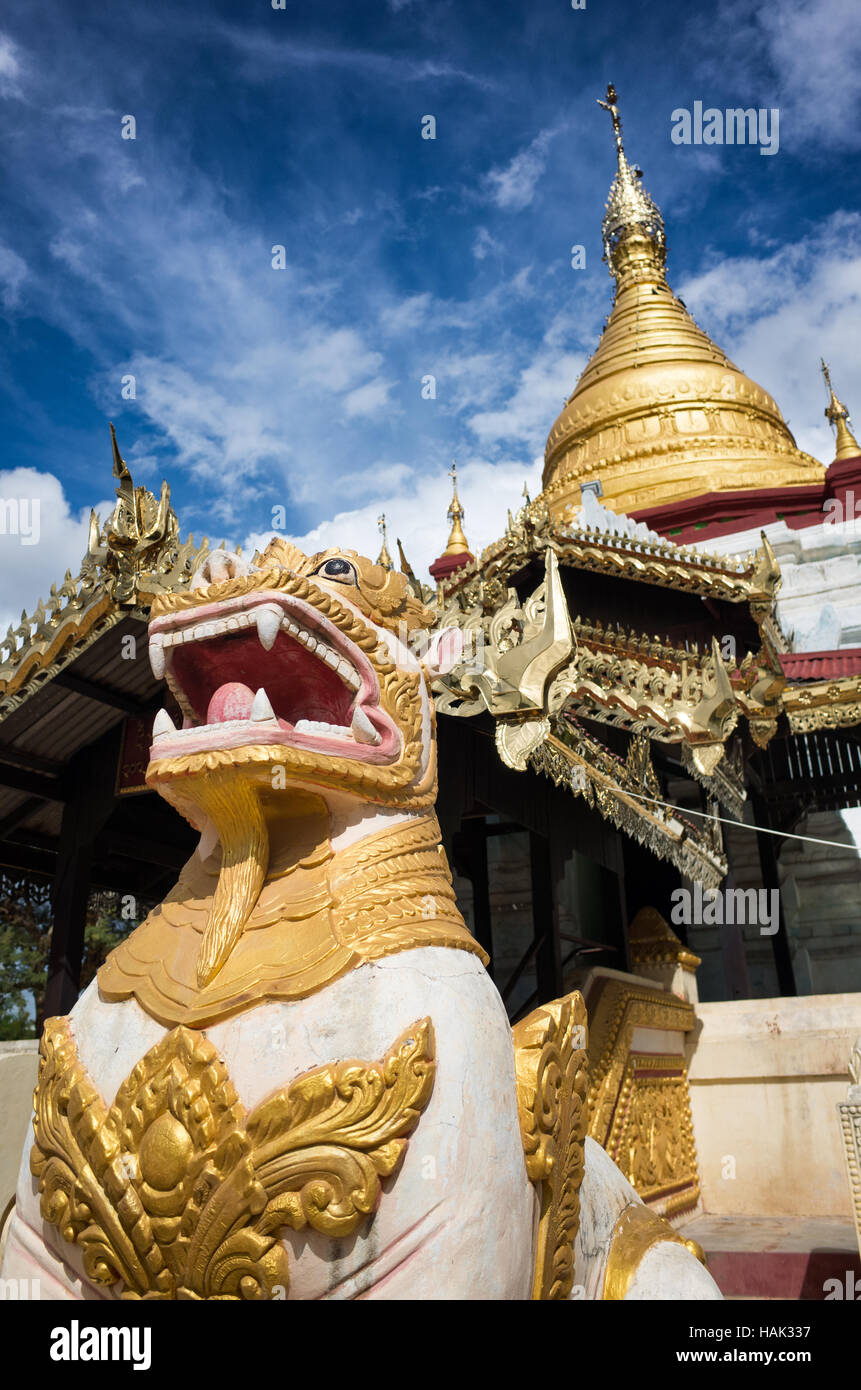 Shwe Kyaung U Temple Chinthe Guardian Bagan Myanmar // BAGAN, Myanmar — statues de gardien de lion ornées connues sous le nom de stand de chinthe devant le stupa doré et architecture élaborée du temple Shwe Kyaung U. Le temple bouddhiste du XVIIIe siècle, documenté comme Monument 2007 dans l'inventaire architectural de Pierre Pichard, est situé dans un monastère au nord-est de Pagan près du village de Taungbi. Le temple présente une construction traditionnelle en maçonnerie de briques avec un pavillon en bois distinctif ajouté sur sa face ouest, reflétant les adaptations faites pour servir la communauté monastique résidente. Shwe Kyaung U Temple Repre Banque D'Images
