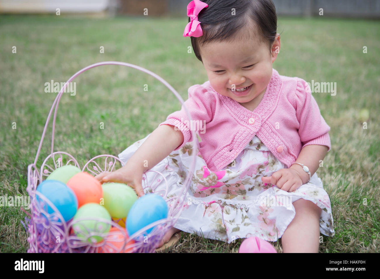 Portrait of Girl wearing Pink et assis sur l'herbe avec Easter basket in Backyard Banque D'Images