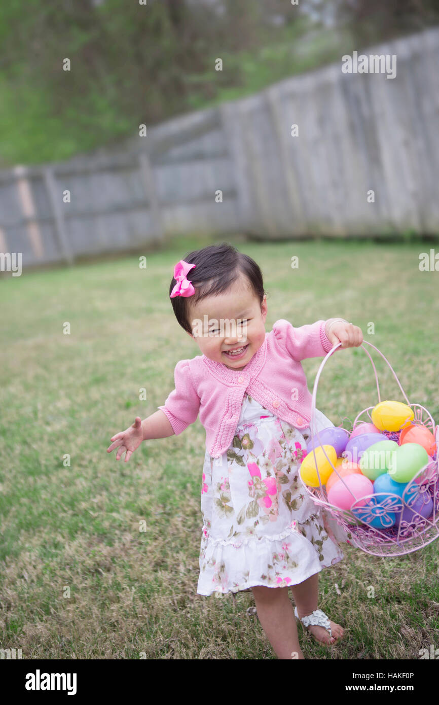 Bébé fille exécutant et souriant avec plein d'oeufs de Pâques Bakset Banque D'Images
