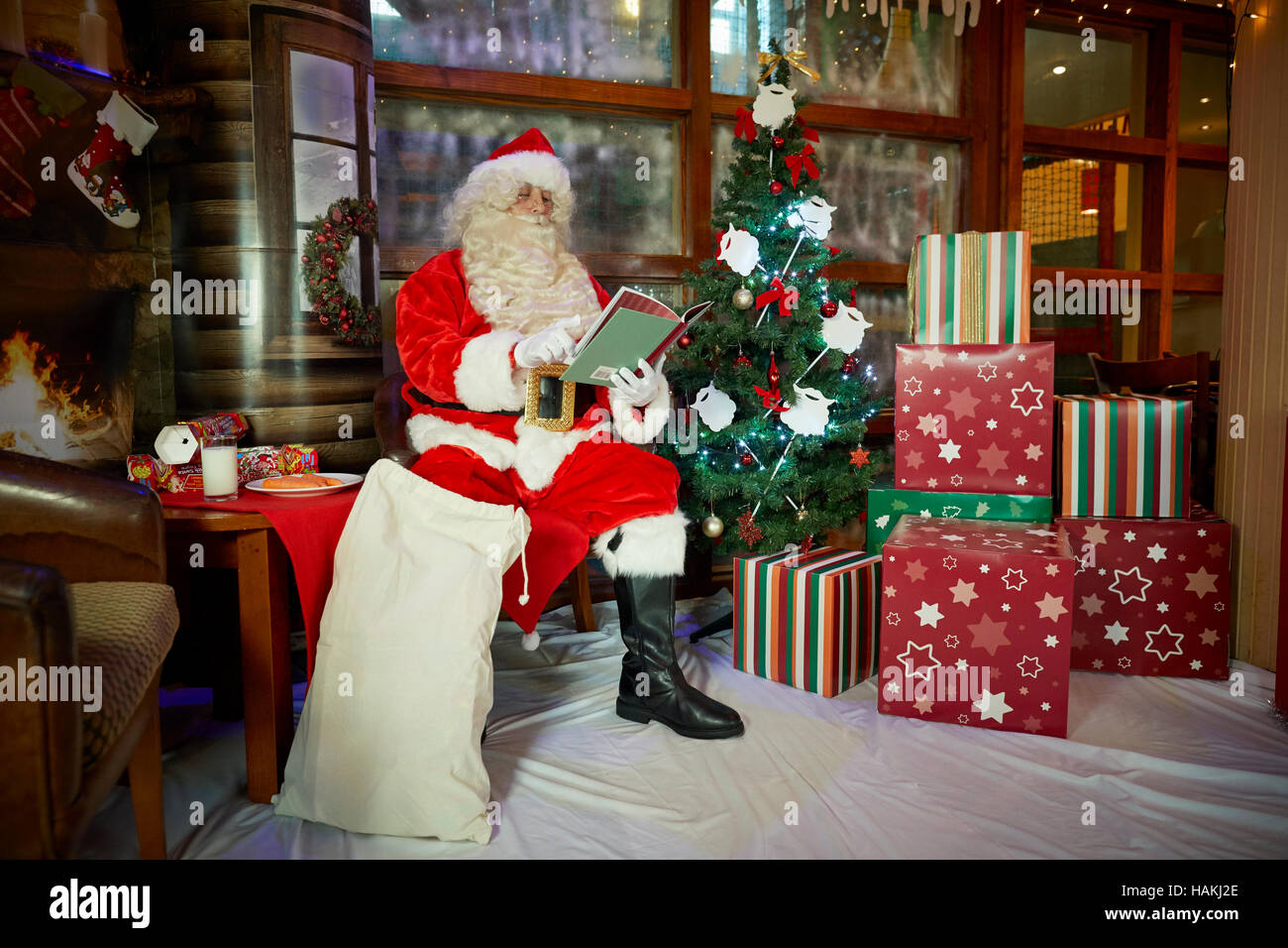 Grotte Santa en affichage de noël arbre de Noël illuminé, présente,cheminée,bas lecture enveloppé doués bon costume rouge sac à pub Santa Cla Banque D'Images