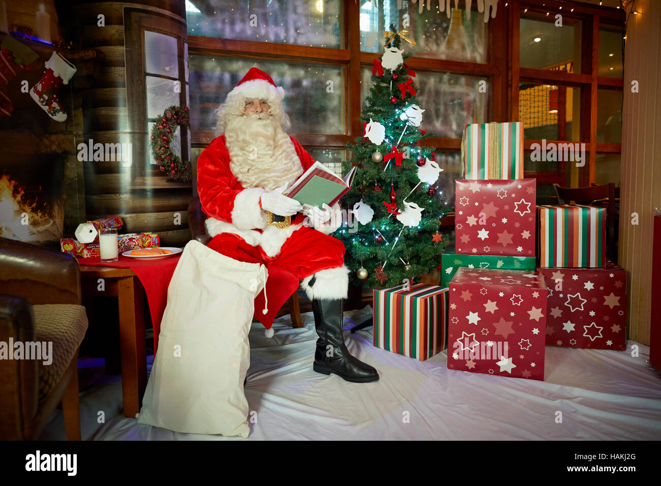 Grotte Santa en affichage de noël arbre de Noël illuminé, présente,cheminée,bas lecture enveloppé doués bon costume rouge sac à pub Santa Cla Banque D'Images