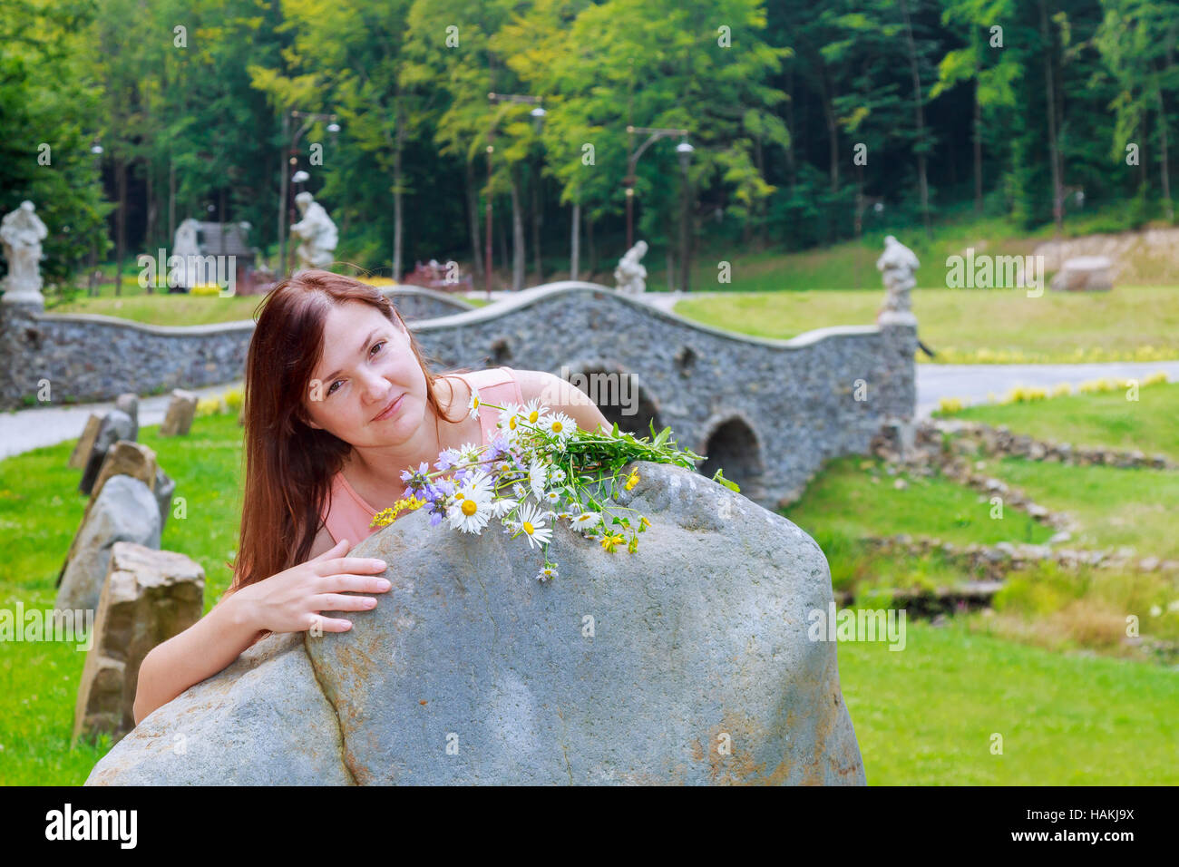 Belle femme avec des fleurs des promenades dans le parc Banque D'Images