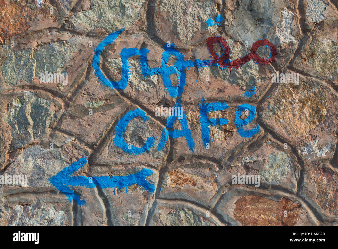 Mur de pierre en plein air, avec un côté 'cafe' en arabe et l'alphabet latin et une flèche indiquant la direction. Banque D'Images