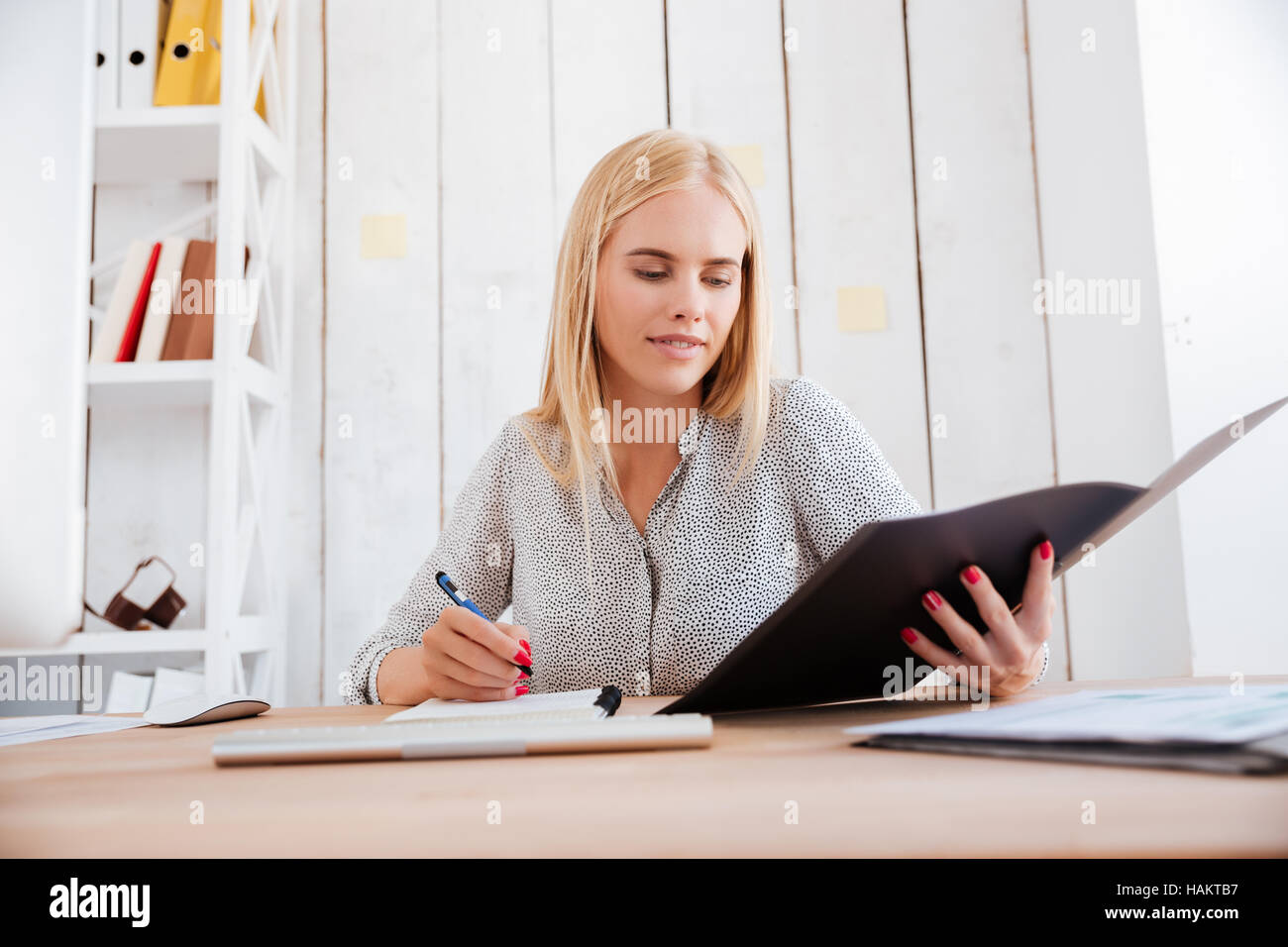Portrait d'un blond woman holding dossier ouvert et prendre des notes Banque D'Images