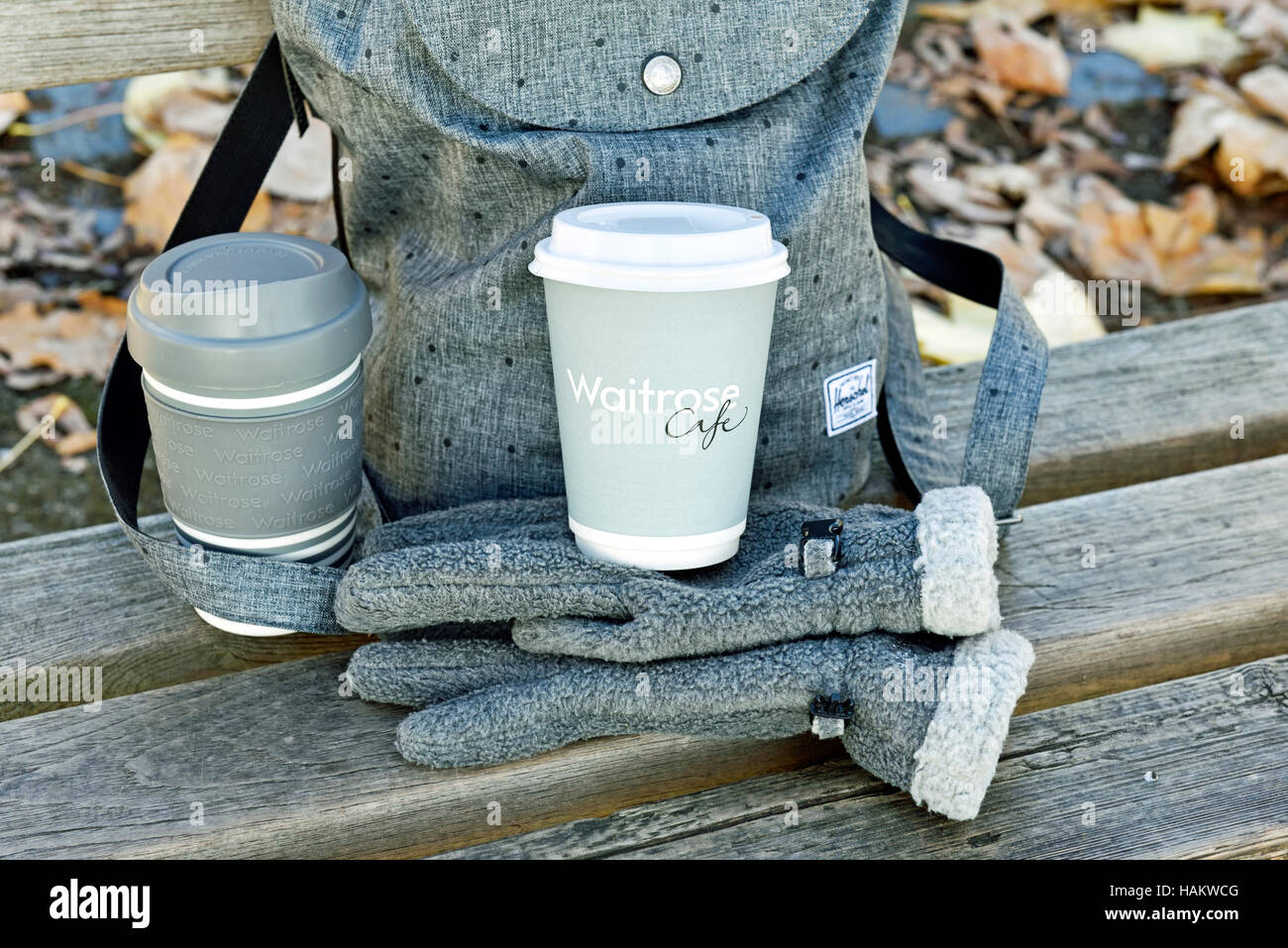 Waitrose emporter jetables avec la tasse de café tasse en plastique réutilisables sur gris Gants polaire en face de sac à dos urbain intelligent. Banque D'Images