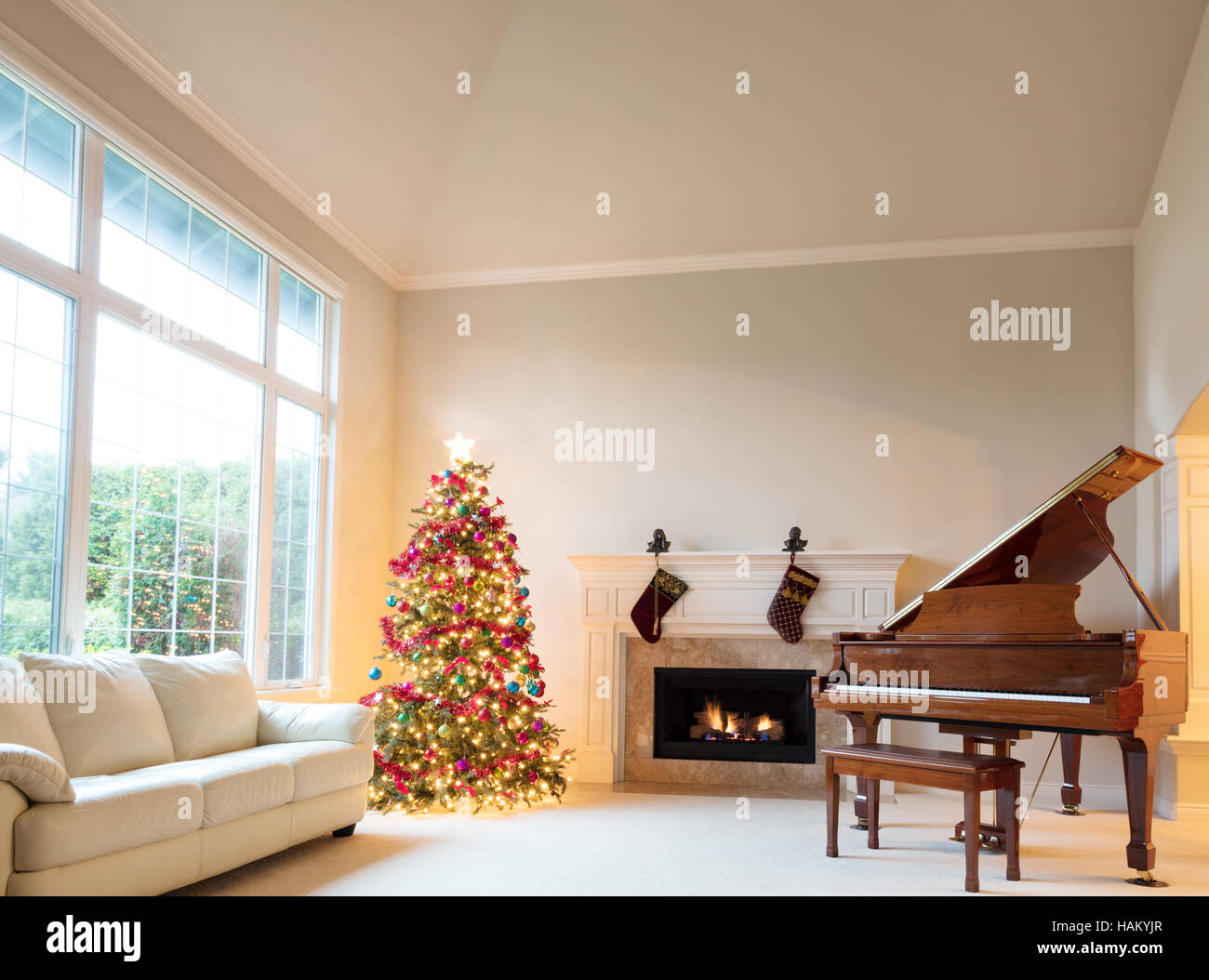 Arbre de Noël dans la salle de séjour avec cheminée et piano pendant la journée lumineuse. Banque D'Images
