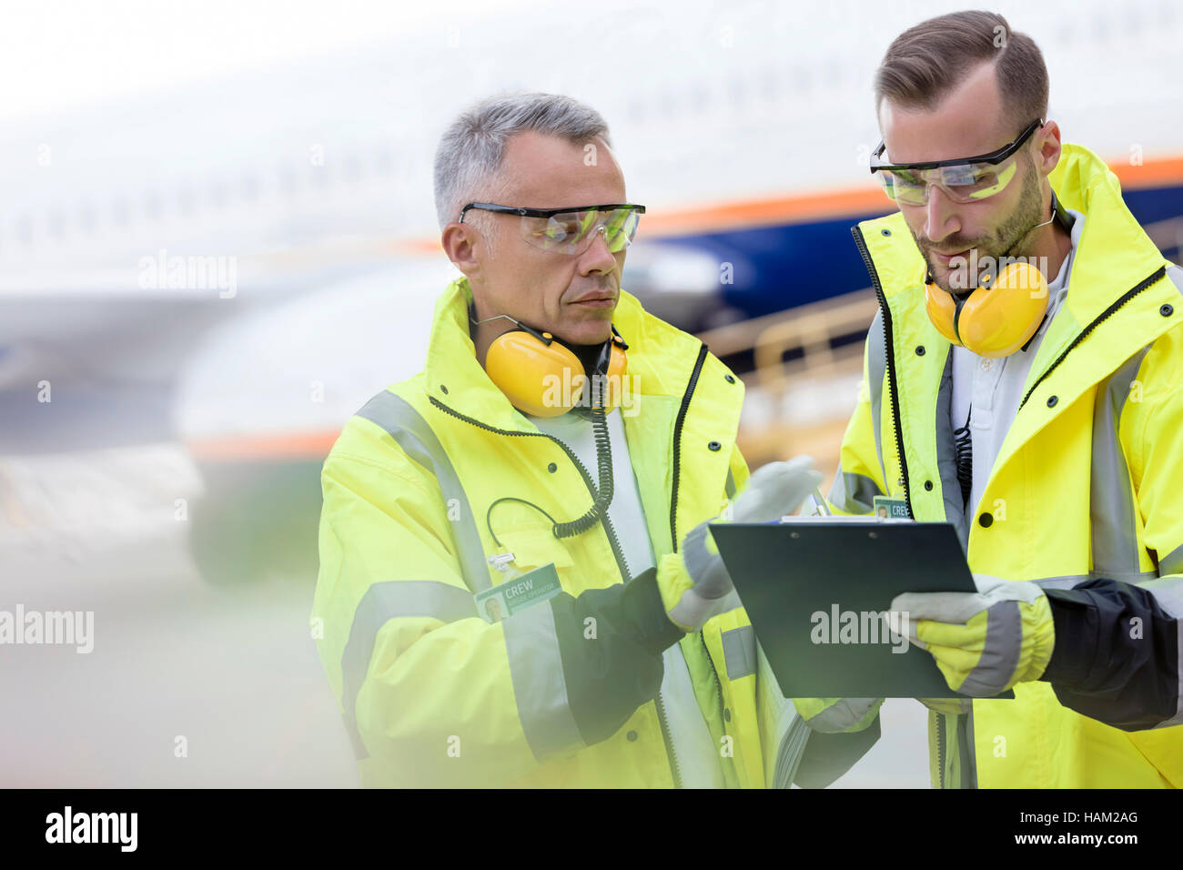 Les contrôleurs du trafic aérien avec le presse-papiers en conversation sur tarmac de l'aéroport Banque D'Images