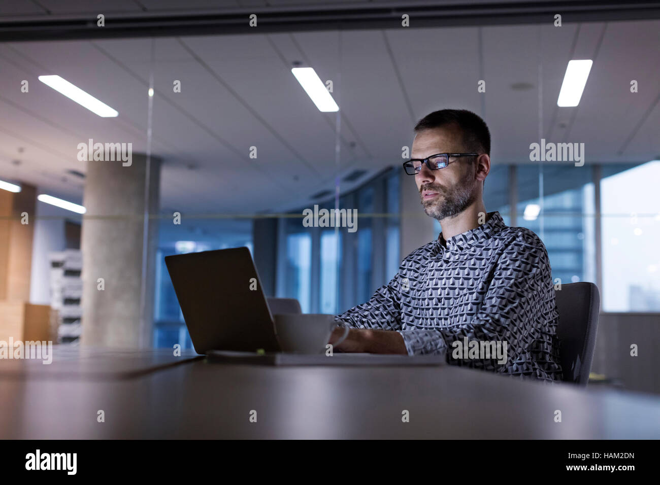 Businessman travaillant tard at laptop in office Banque D'Images