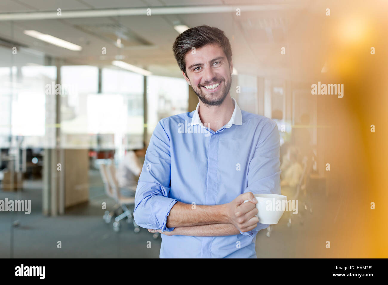 Portrait confident businessman drinking coffee in office Banque D'Images