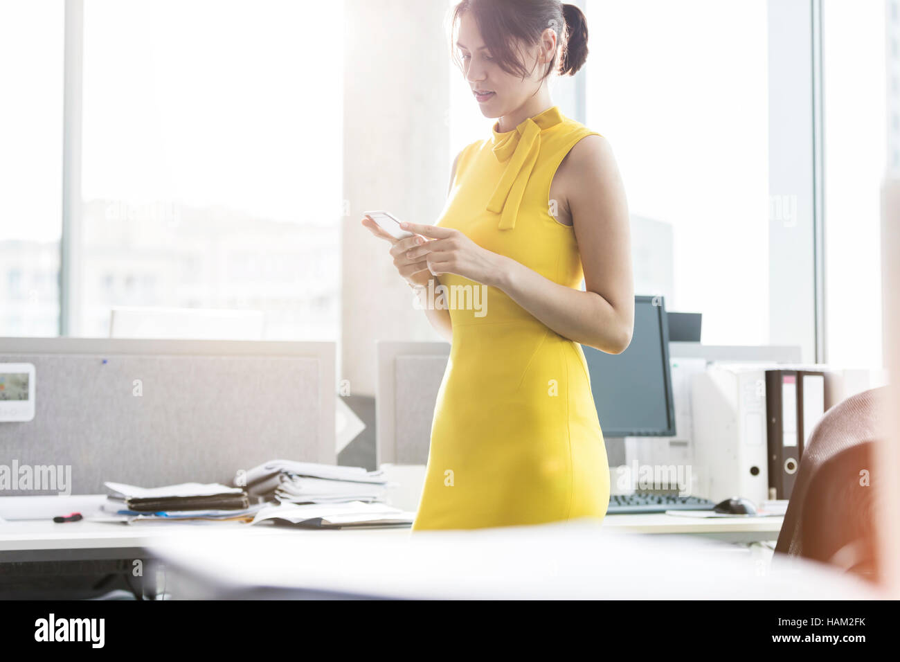 Businesswoman texting with cell phone in office Banque D'Images