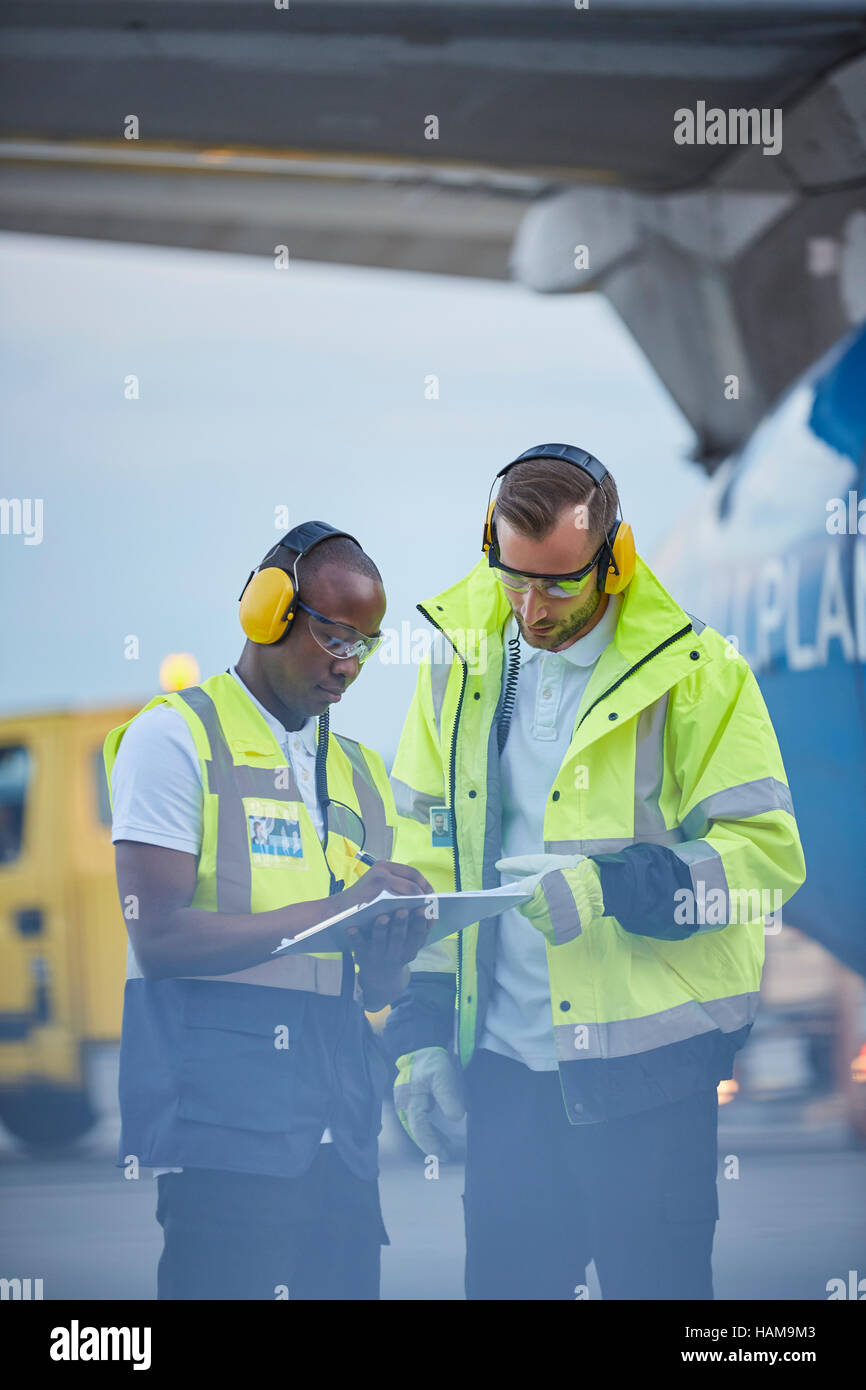 Les contrôleurs du trafic aérien avec le presse-papiers en conversation sur tarmac de l'aéroport Banque D'Images