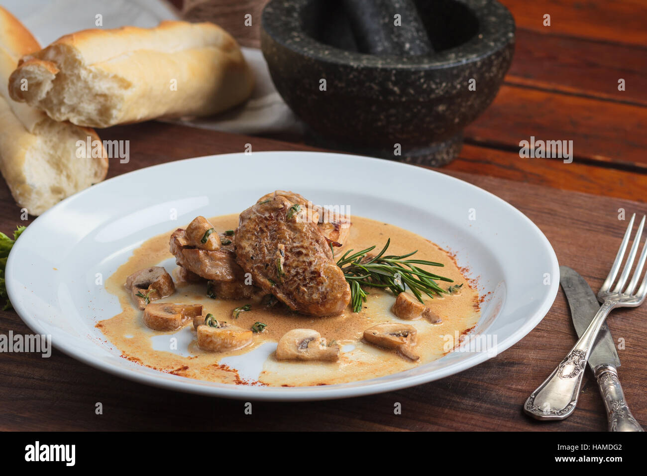 Concept : Les menus de restaurant, d'une saine alimentation, faits maison, gourmands, la gourmandise. Plaque blanche de médaillons de porc sauce aux champignons sur table en bois patiné Banque D'Images