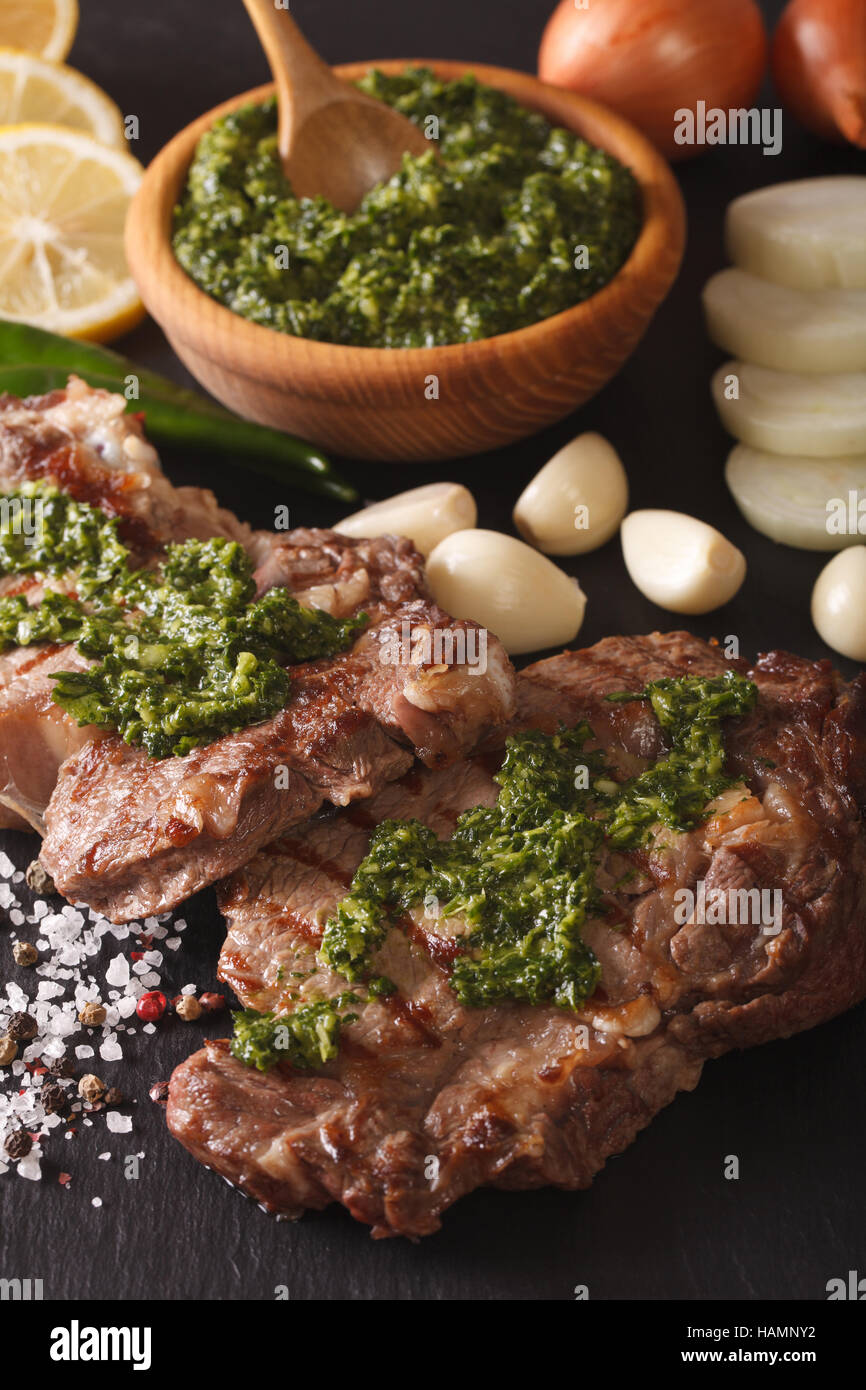 Cuisine argentine : Pavé de boeuf grillé avec sauce Chimichurri macro sur la table. La verticale Banque D'Images
