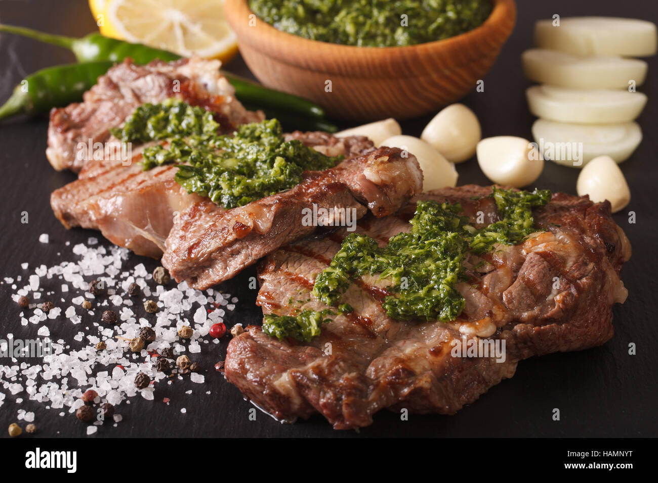 Cuisine argentine : Pavé de boeuf grillé avec sauce Chimichurri macro sur la table horizontale. Banque D'Images