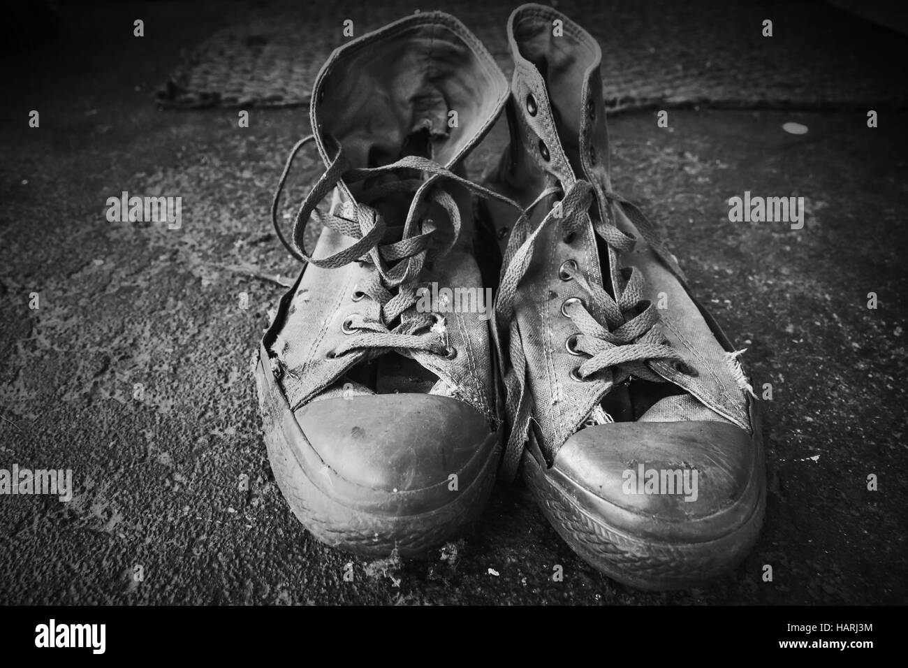 Les vieilles chaussures de se tenir sur un sol en béton. Photo en noir et blanc gros plan Banque D'Images