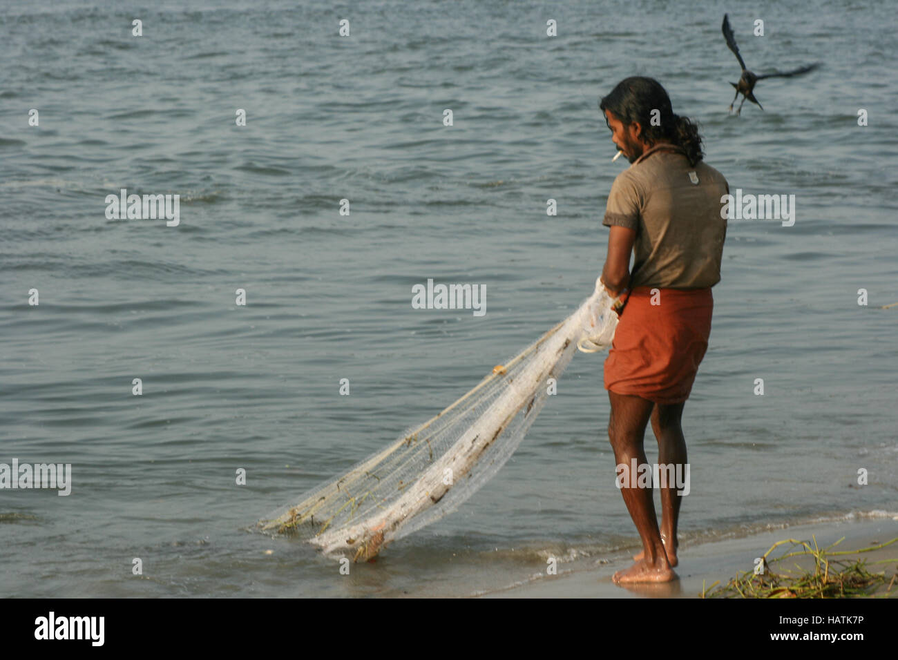 Un jeune pêcheur indien fumer dans un hawling lungi tirant dans son filet  de pêche de la plage, de l'Inde Photo Stock - Alamy