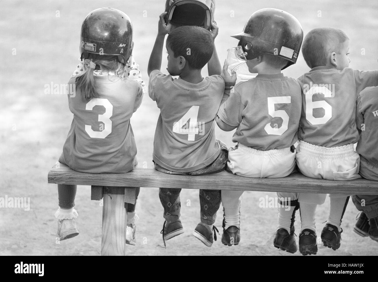 Quatre jeunes joueurs de base-ball portant des numéros séquentiels. Banque D'Images