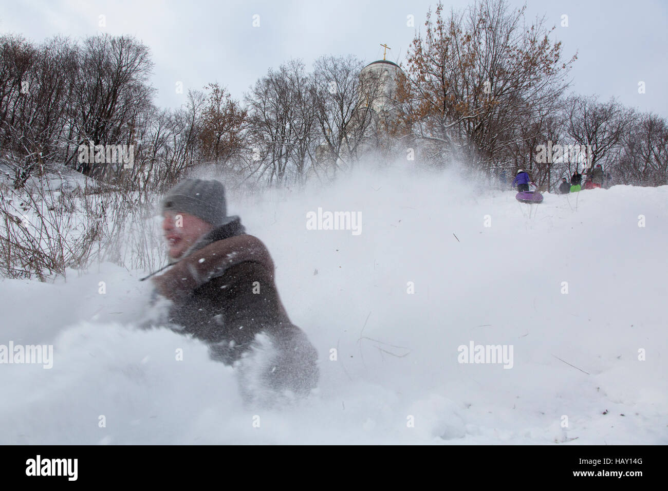 Le traîneau à cheval les jeunes à partir de la pente de neige des chutes de neige au parc de Moscou, Russie Banque D'Images