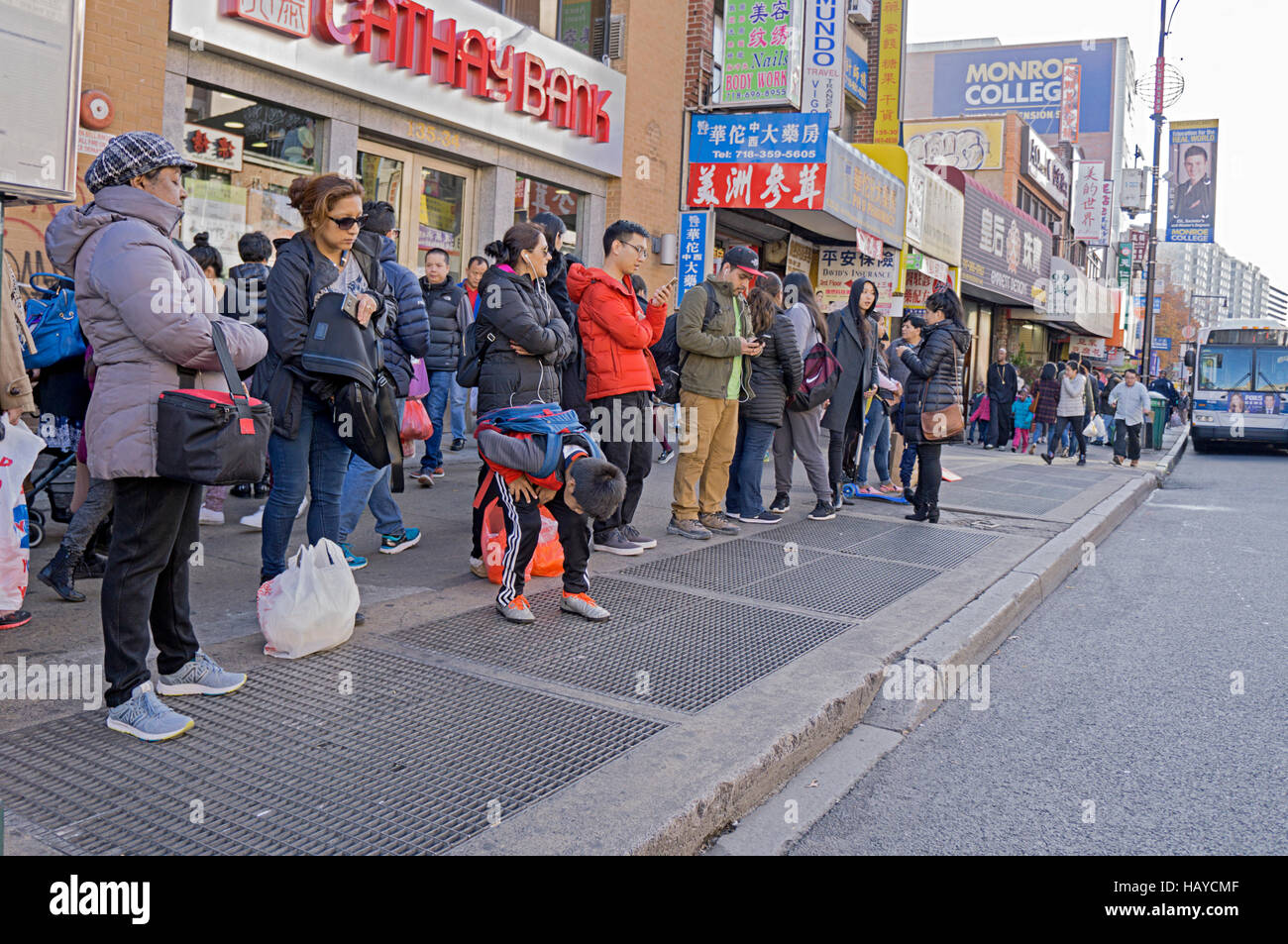Une longue file de personnes qui attendent un bus dans le quartier chinois, le centre-ville de Flushing, New York. Banque D'Images