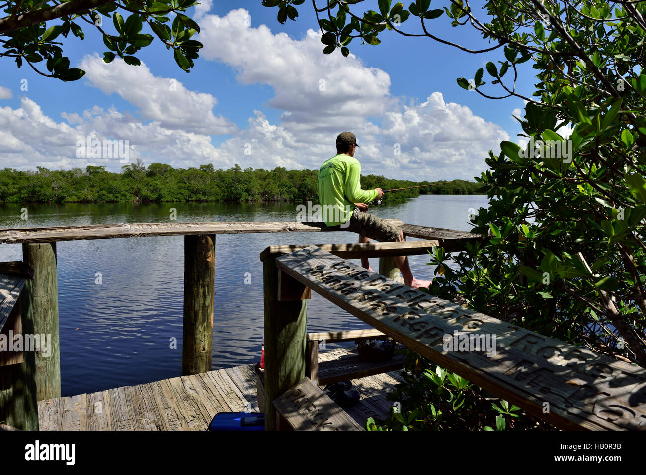 Assis sur la balustrade de bois la pêche au large de Boardwalk à Saint James Creek à la fin de saint Jude Nature Trail, Pine Island, Floride Banque D'Images