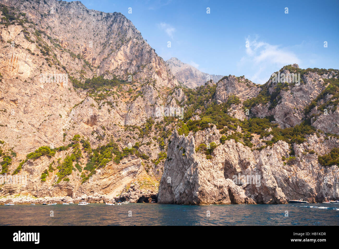 Paysage avec côte rocheuse de l'île de Capri, Mer Méditerranée, l'Italie. Petit bateau de plaisance entre dans la grotte côtière Banque D'Images